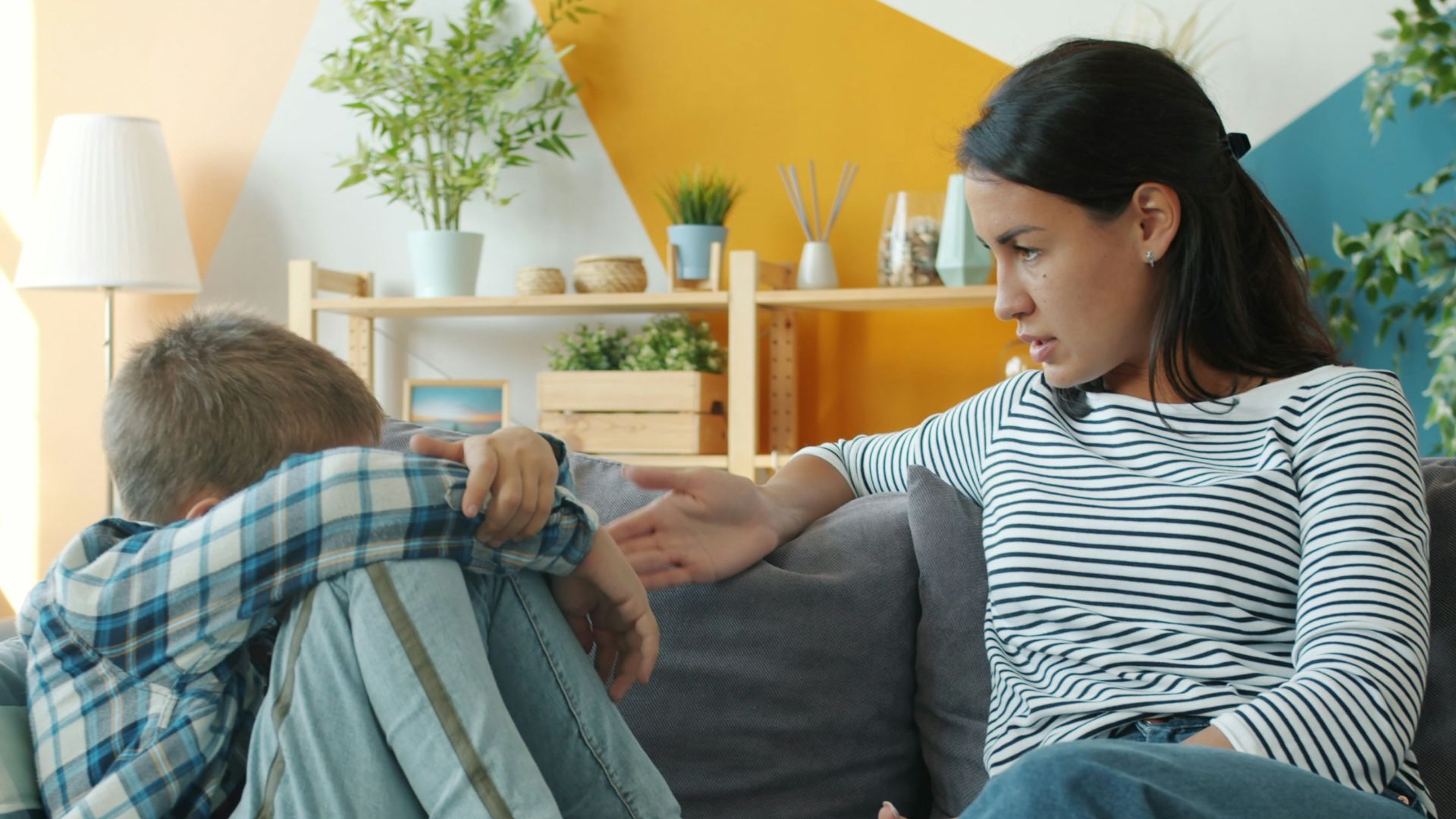 Mother comforts upset child on the sofa