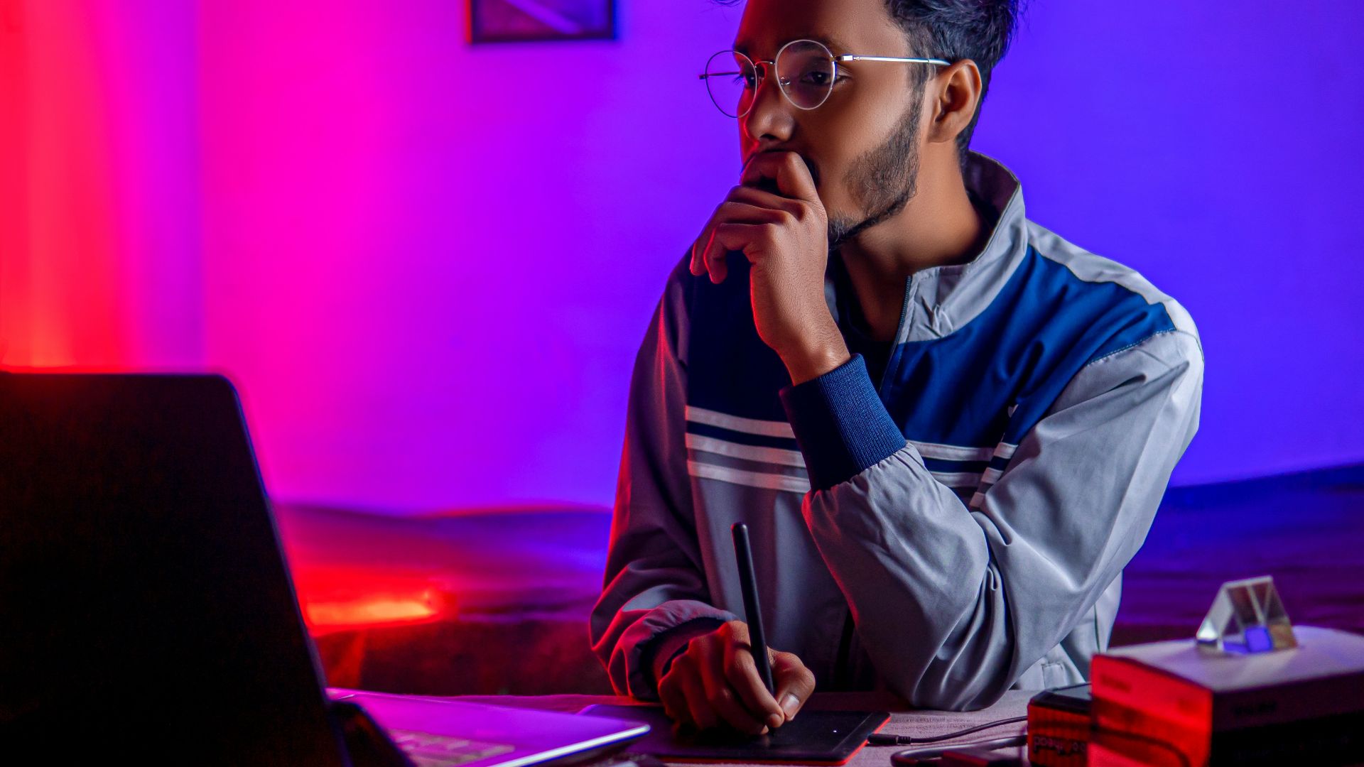 a person sitting at a desk with a laptop and a computer