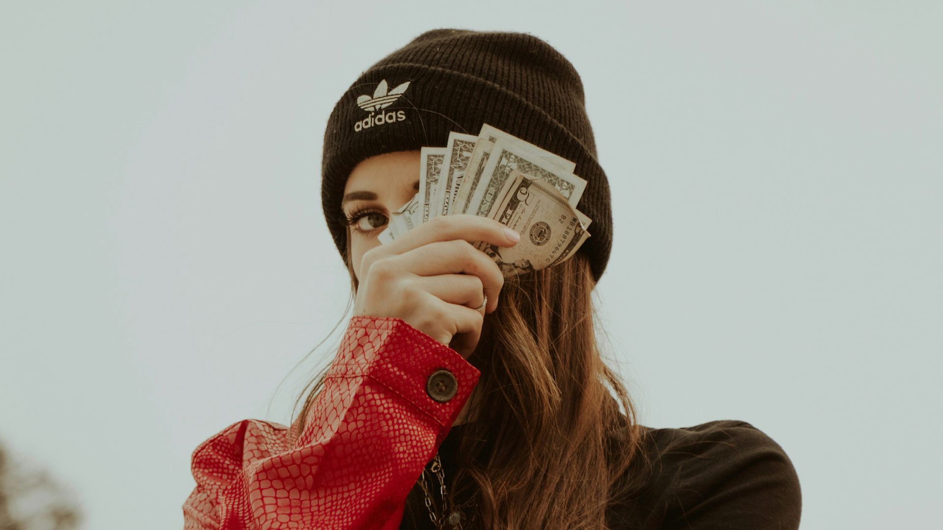 woman in black knit cap covering her face with her hand