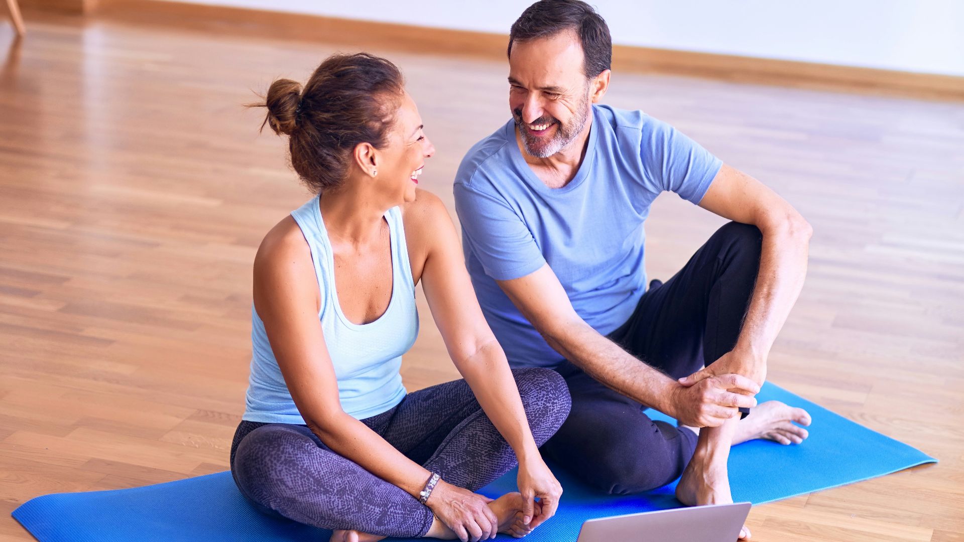 man in white tank top and gray pants sitting on blue yoga mat