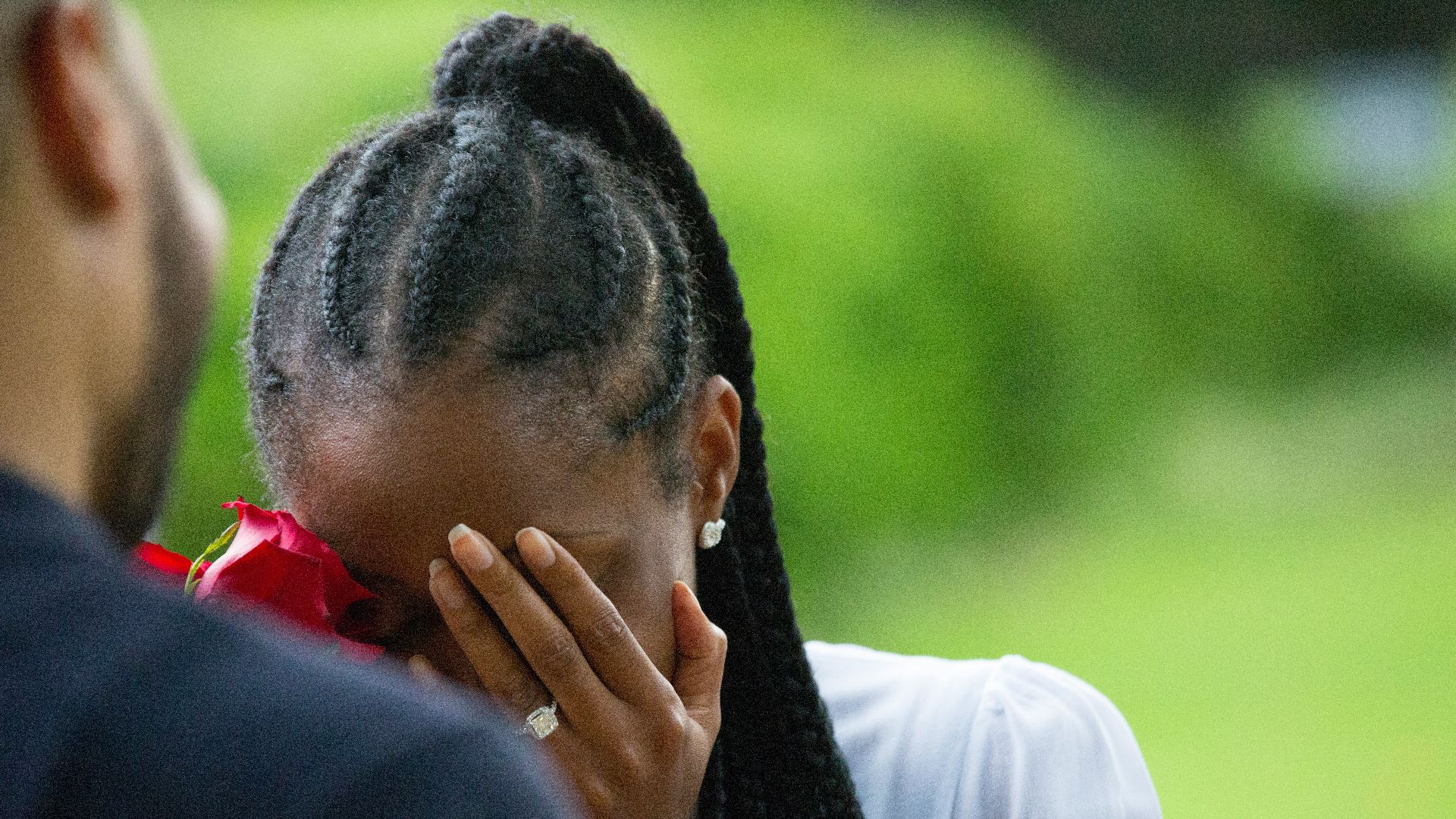 woman wearing white shirt holding rose covering face