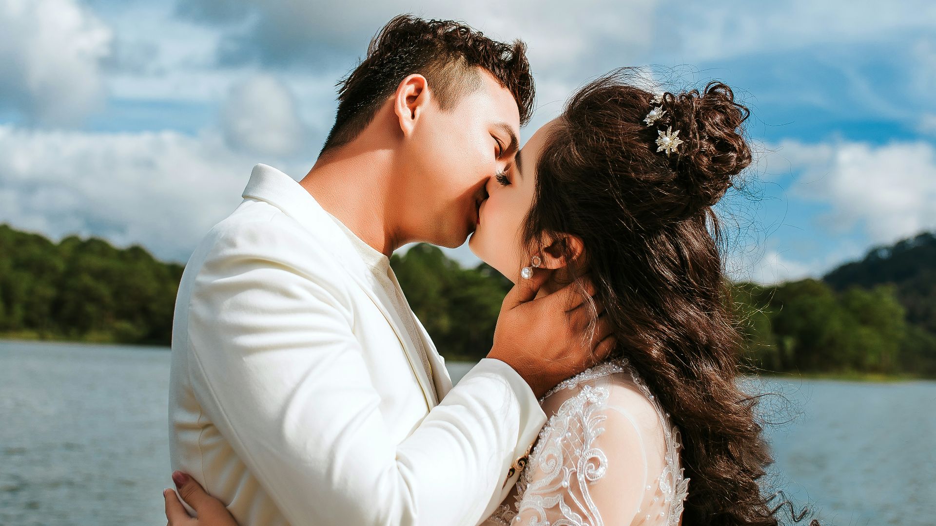 a bride and groom kissing in front of a lake