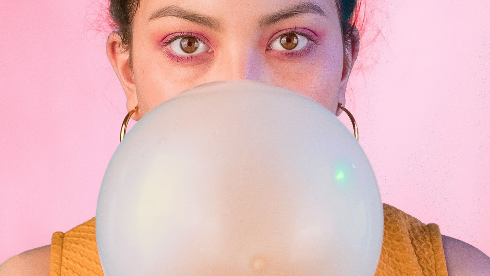 woman in yellow sleeveless shirt blowing gum