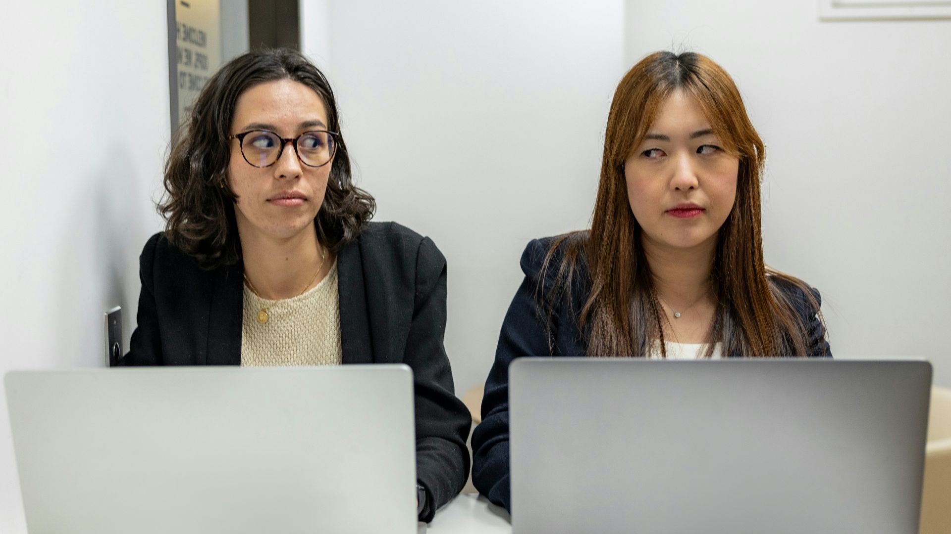 two women sitting at a table with laptops