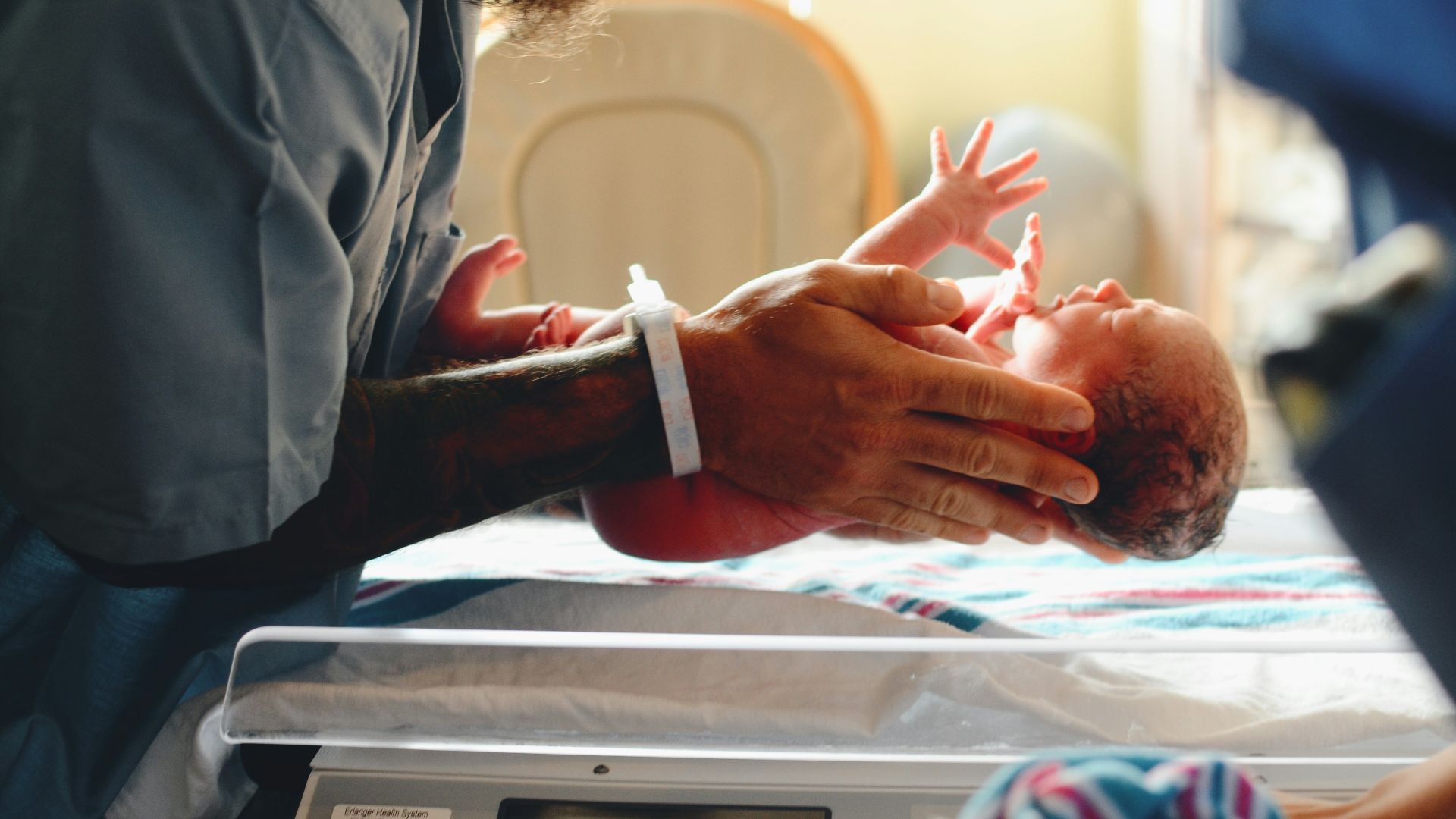 person wearing gray shirt putting baby on scale