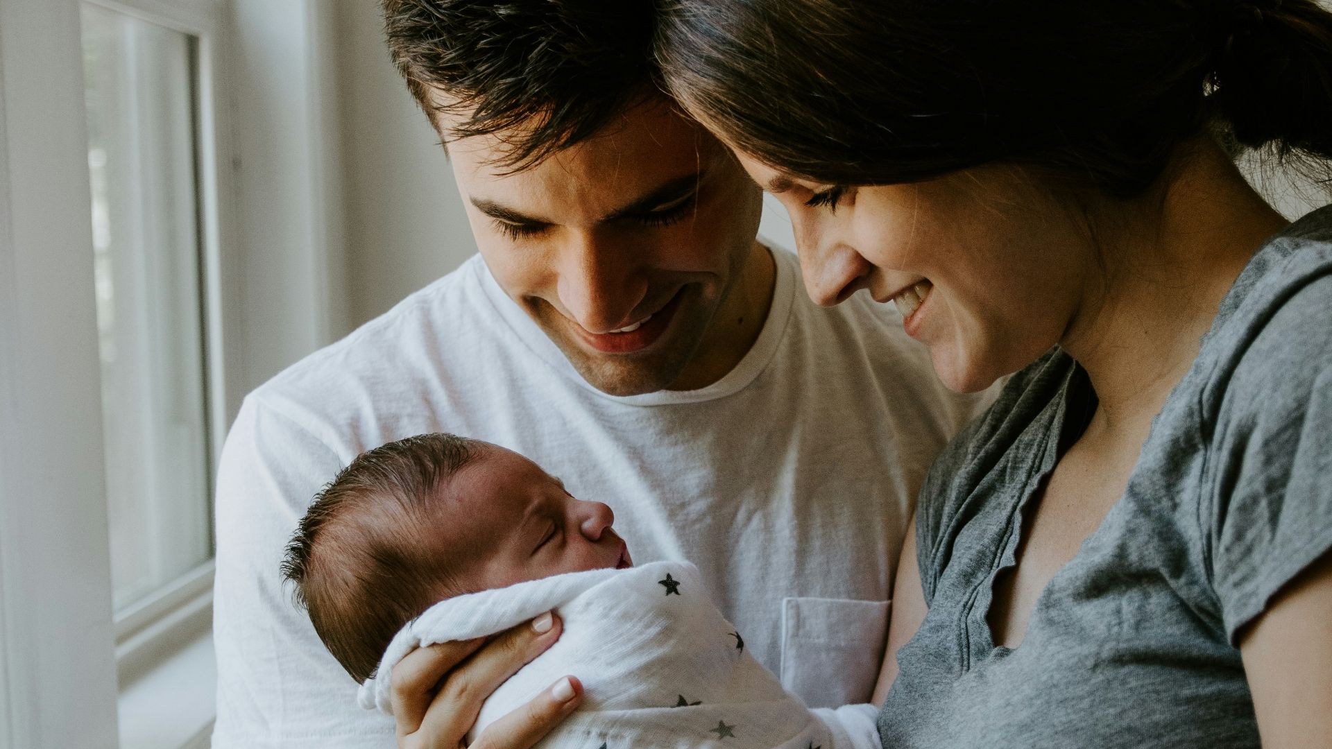 woman holding baby beside man smiling