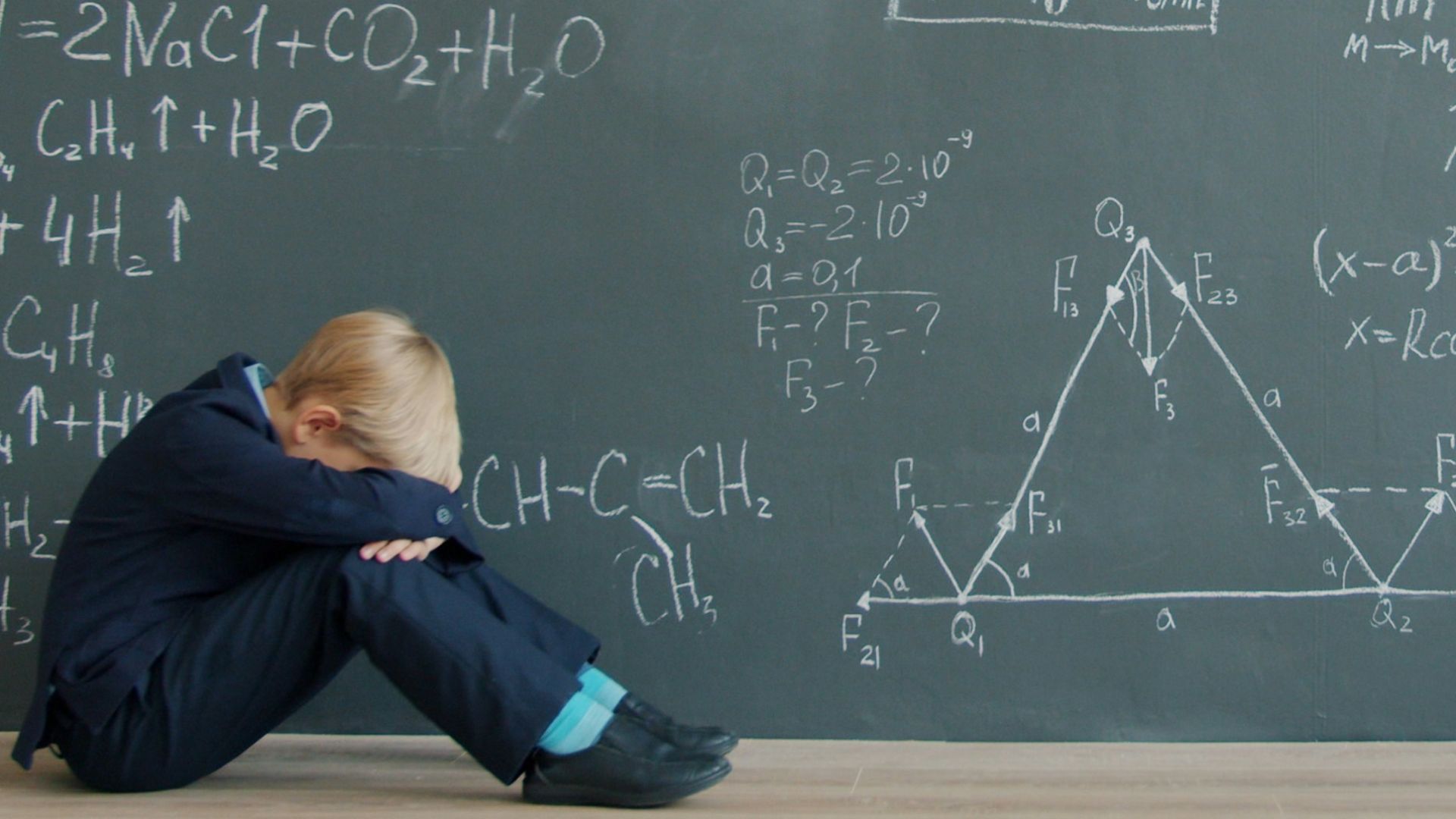 Student sits by blackboard covered in math equations
