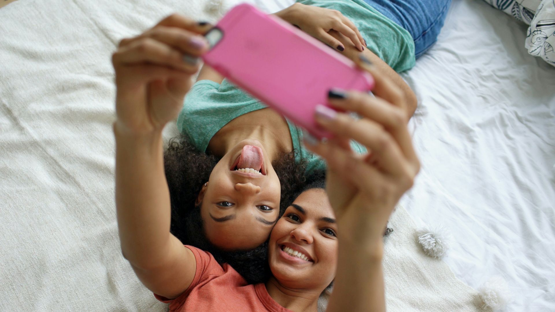 Two friends taking a selfie on a bed
