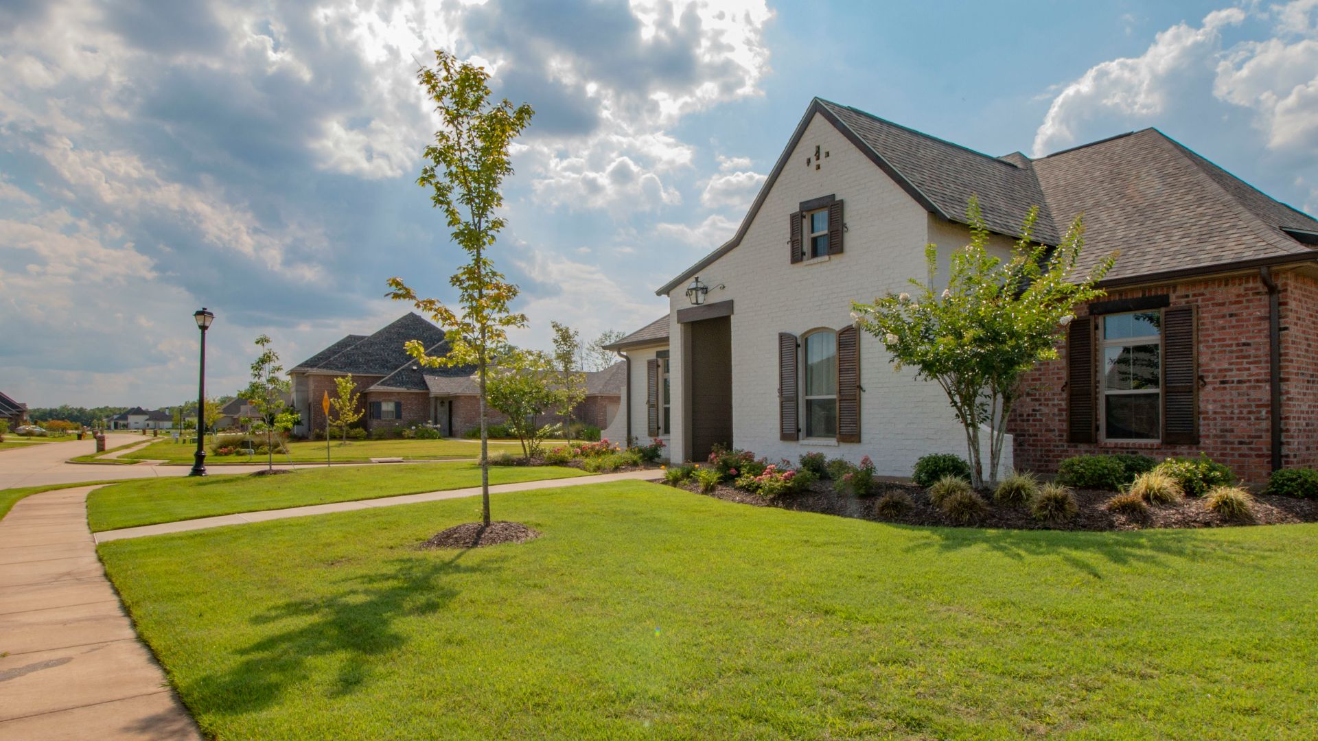 white and brown house near green grass field under white clouds and blue sky during daytime