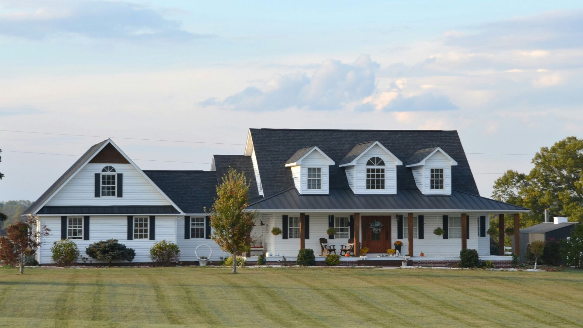 A large white farmhouse with a wrap-around porch.