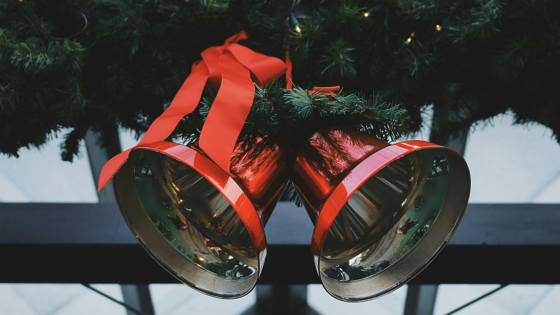 two red steel bells beside green Christmas decoration