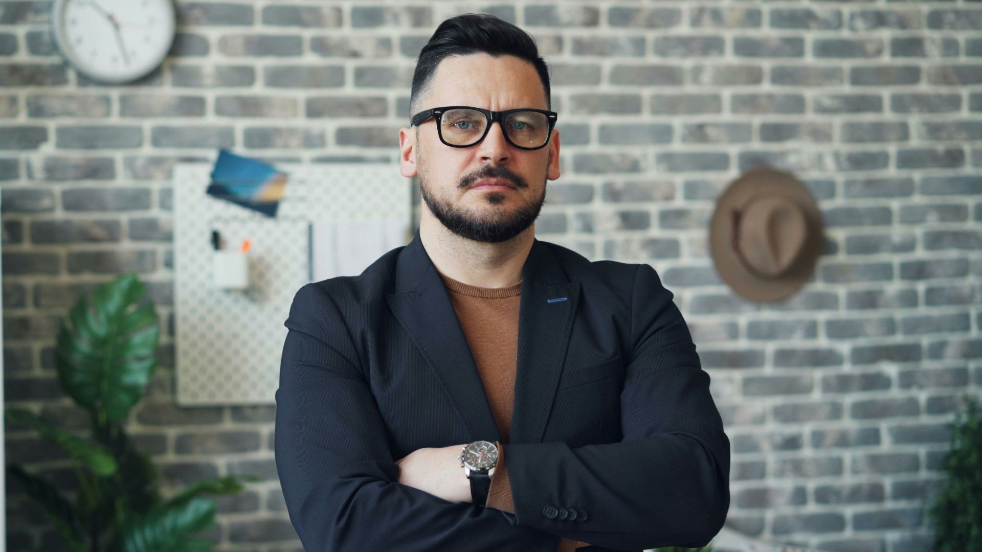 a man in a suit standing in front of a brick wall