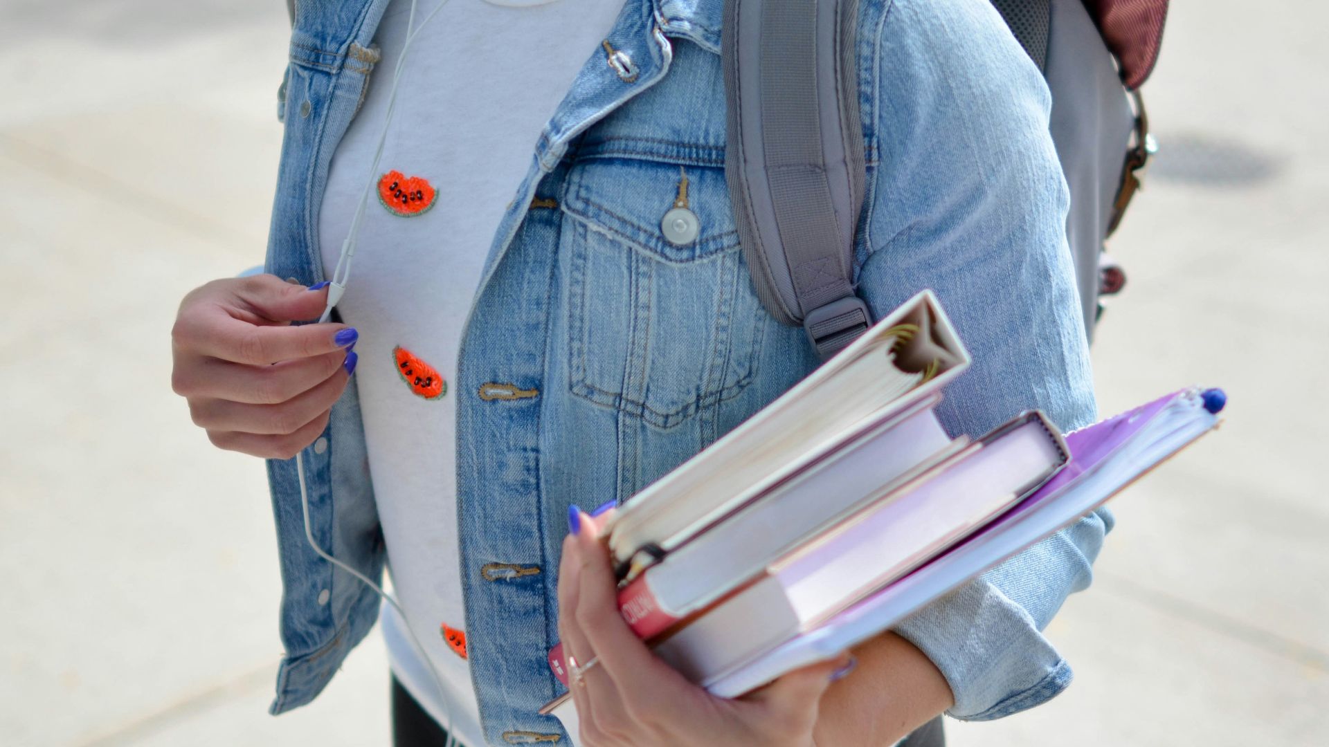 woman wearing blue denim jacket holding book