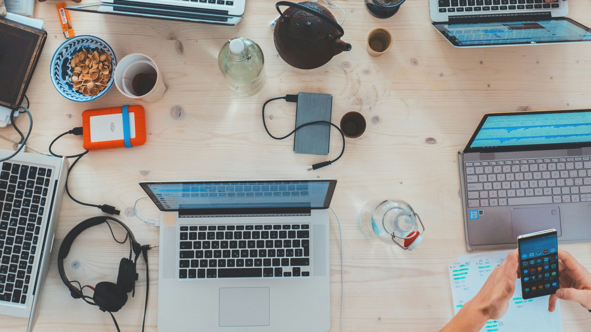 people sitting down near table with assorted laptop computers