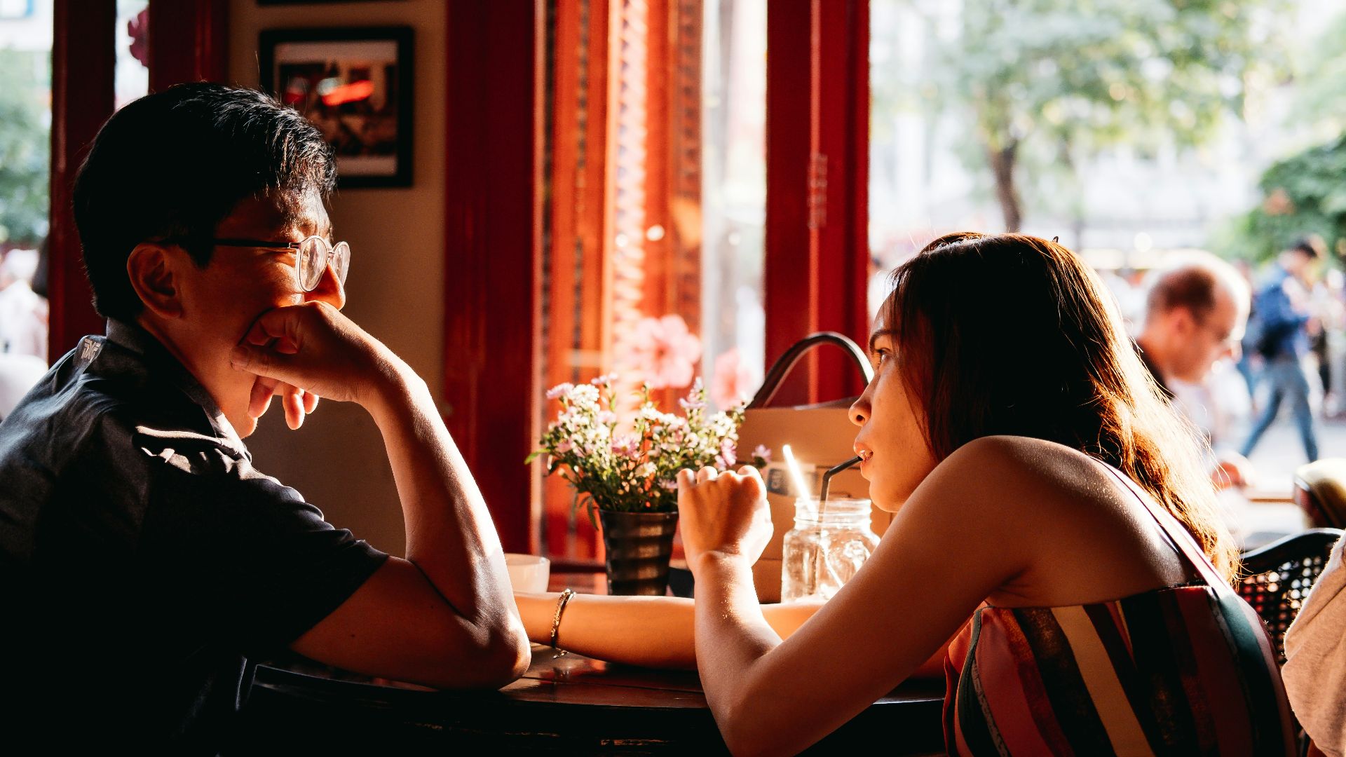man wearing black collared top sitting on chair in front of table and woman wearing multicolored top