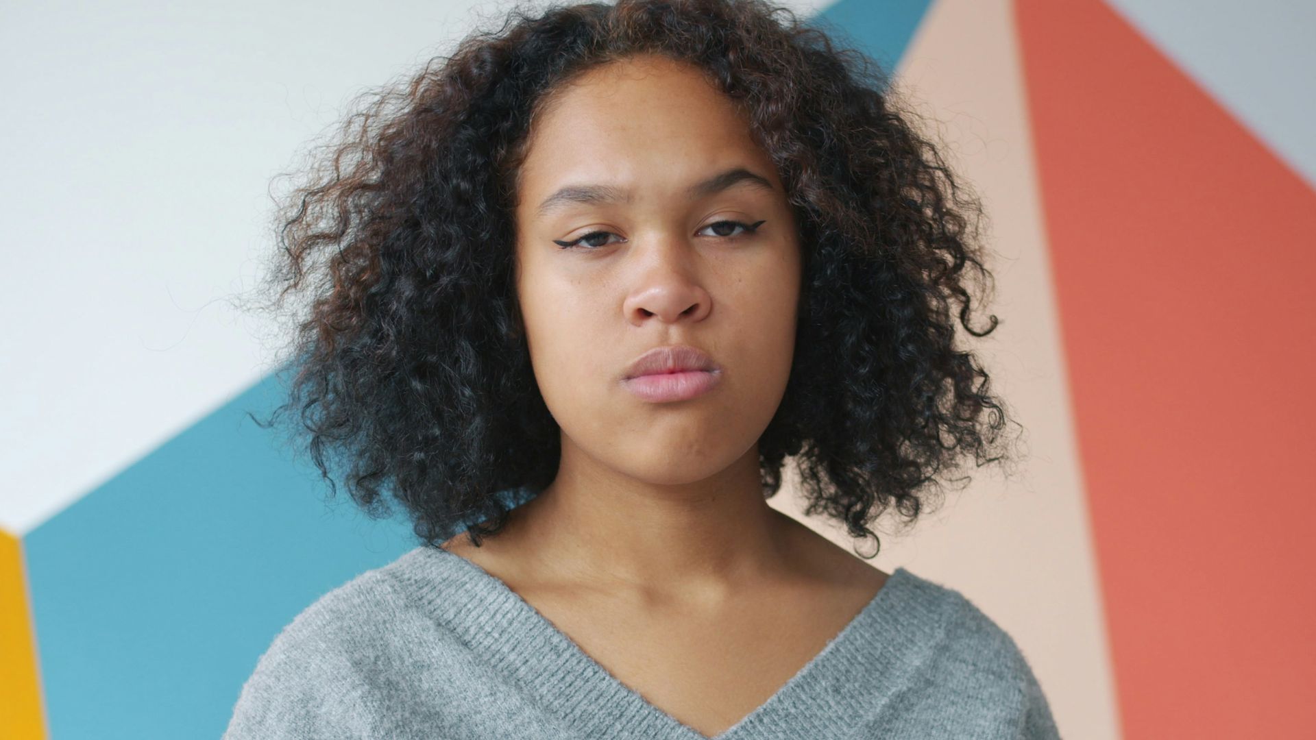 Young woman with curly hair against colorful wall