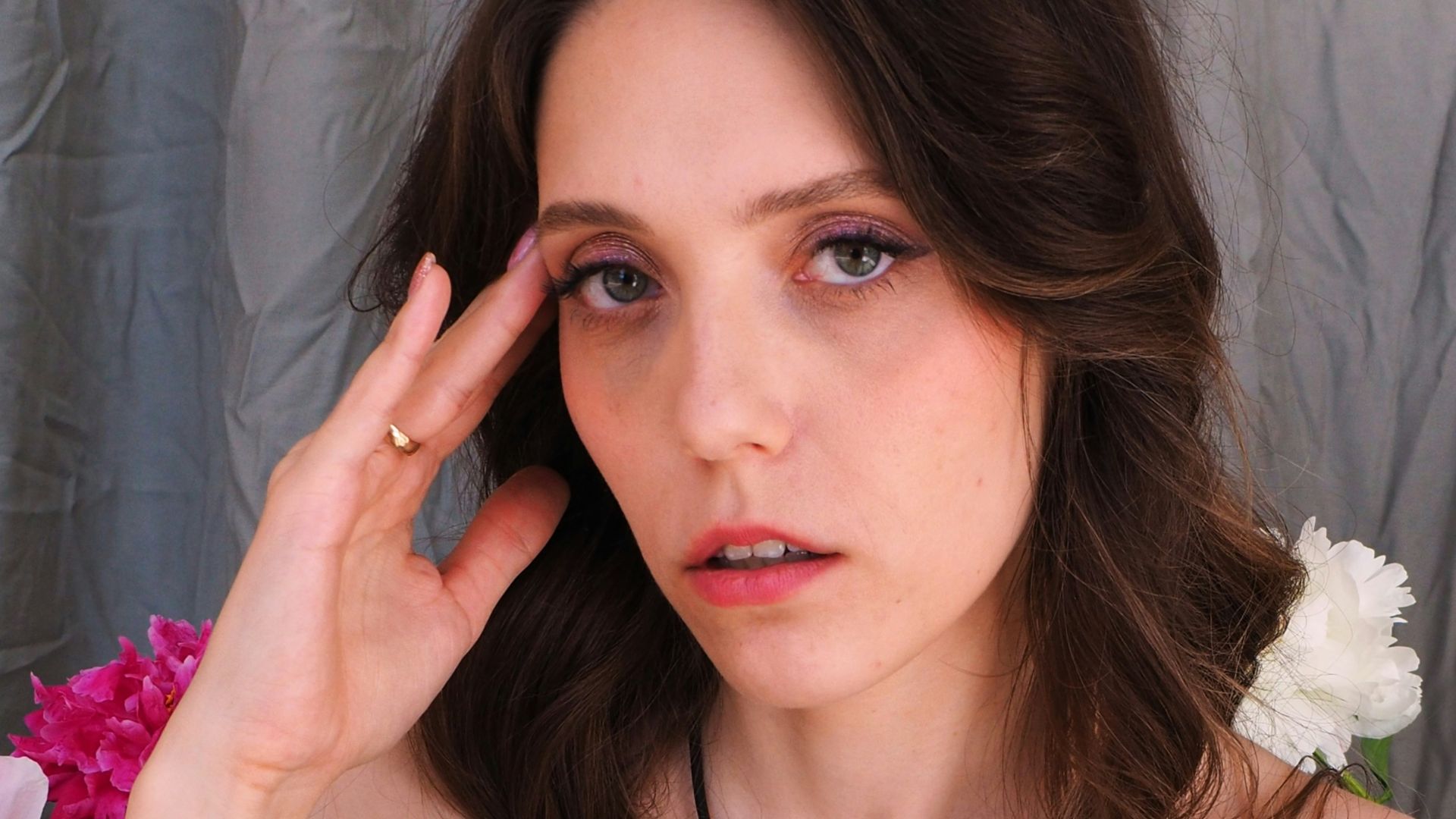 A woman in a blue dress holding her hand up to her face