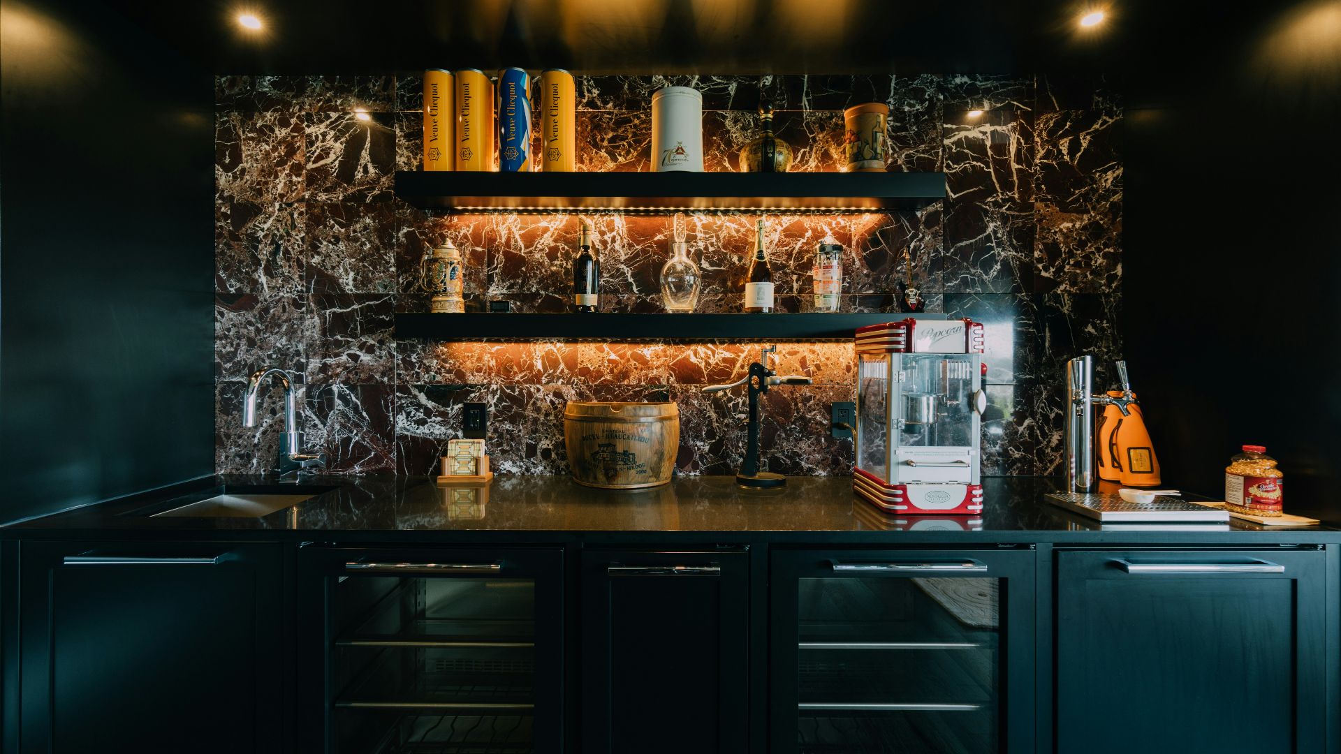 a kitchen with black cabinets and marble counter tops