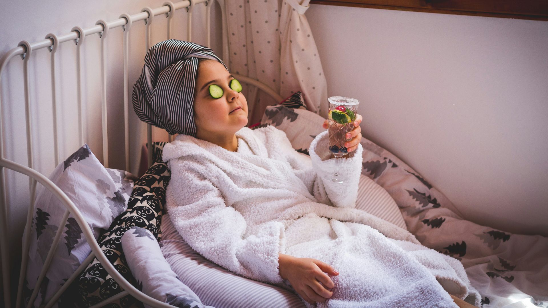 baby in white sweater and yellow goggles lying on bed