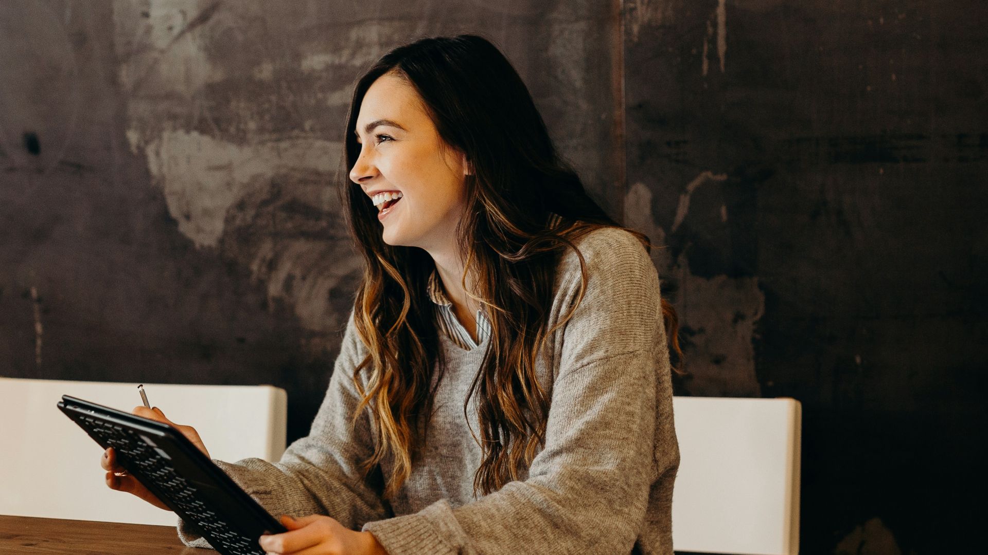 woman sitting around table holding tablet