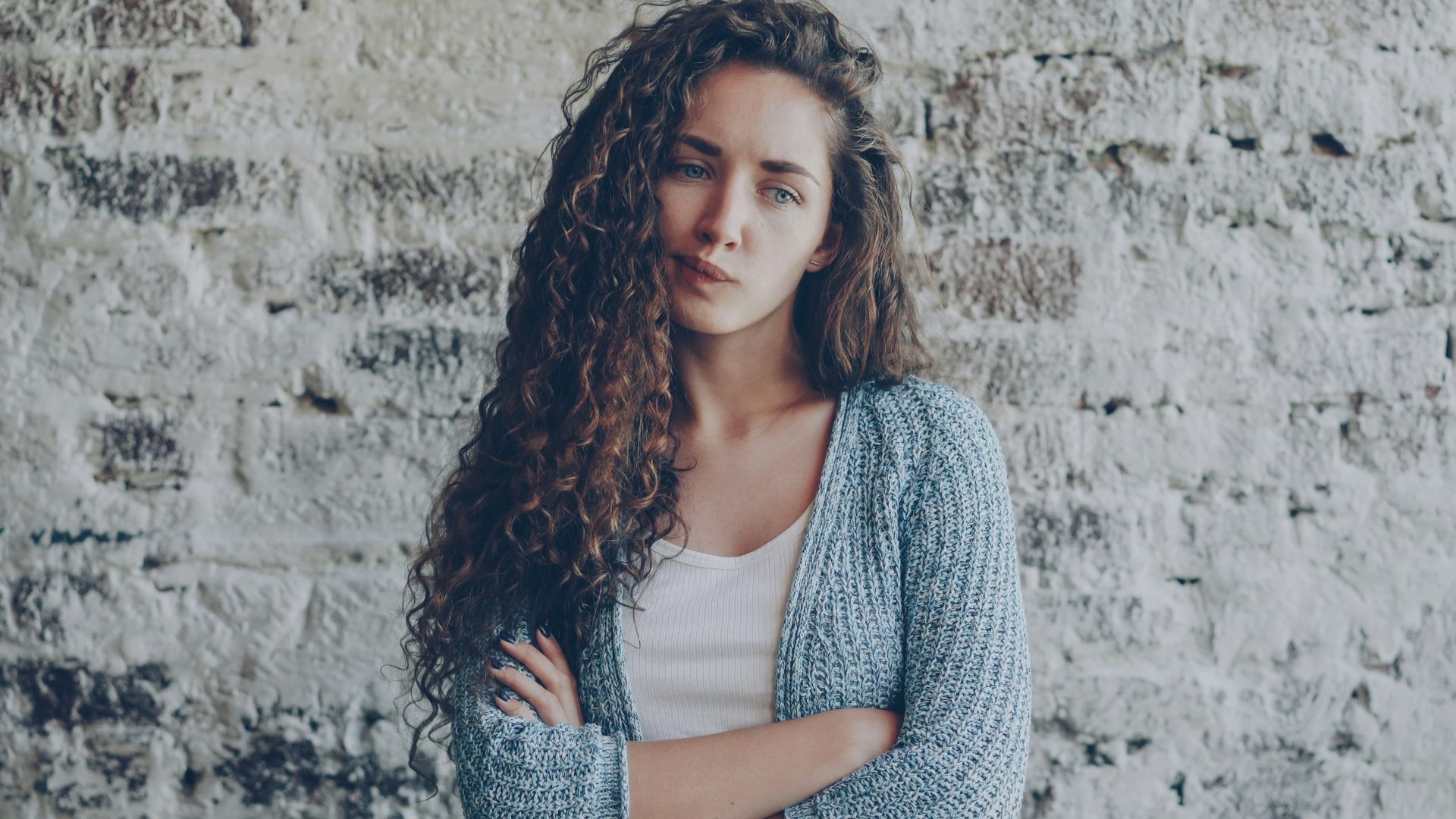 Young woman with curly hair crosses arms