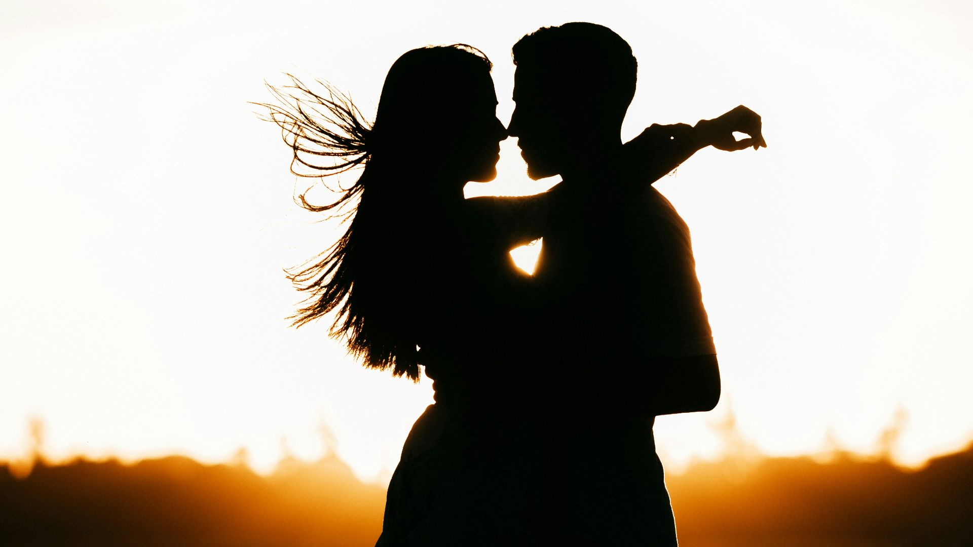 silhouette of woman standing on beach during sunset