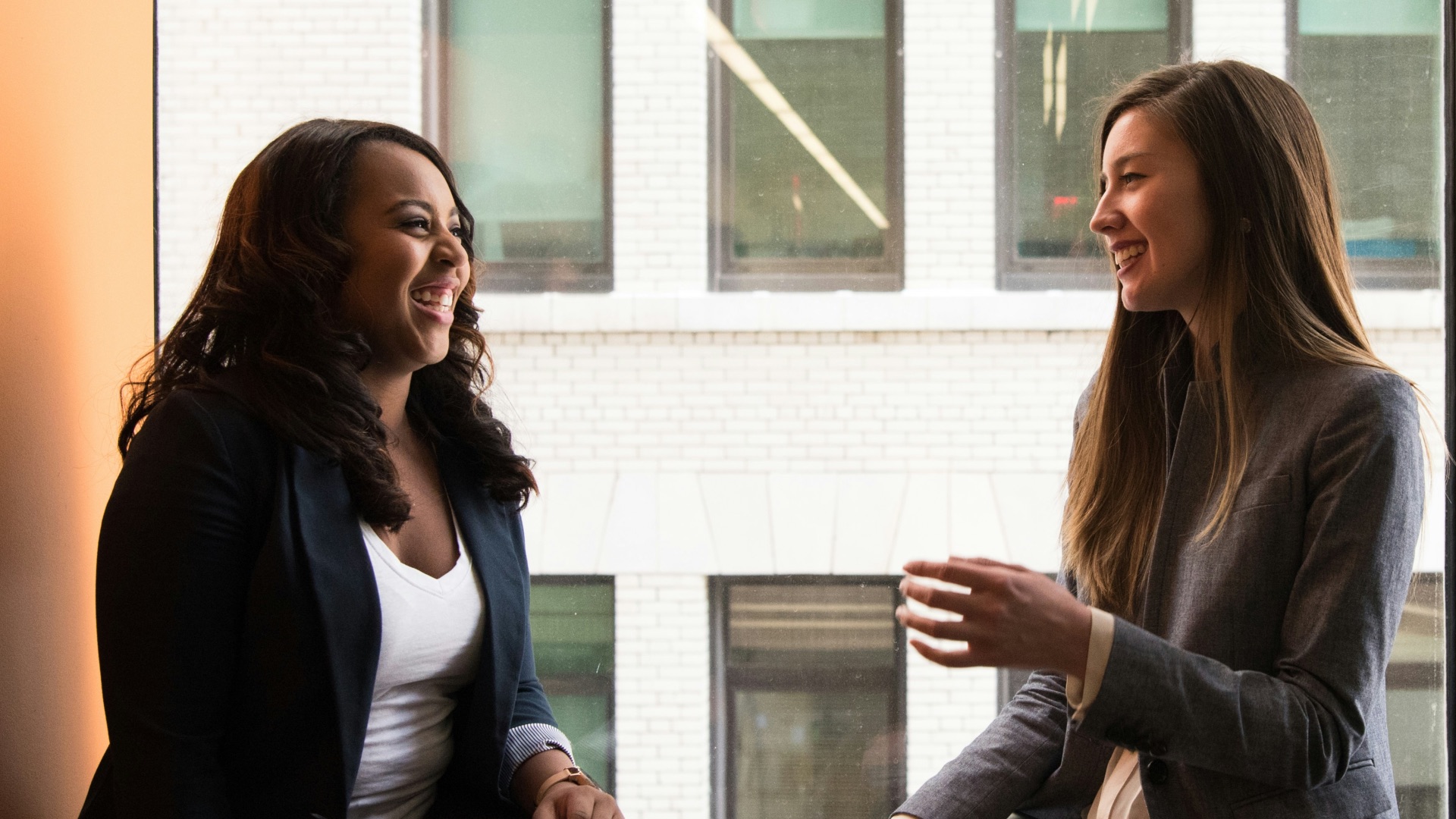 two woman sitting by the window laughing