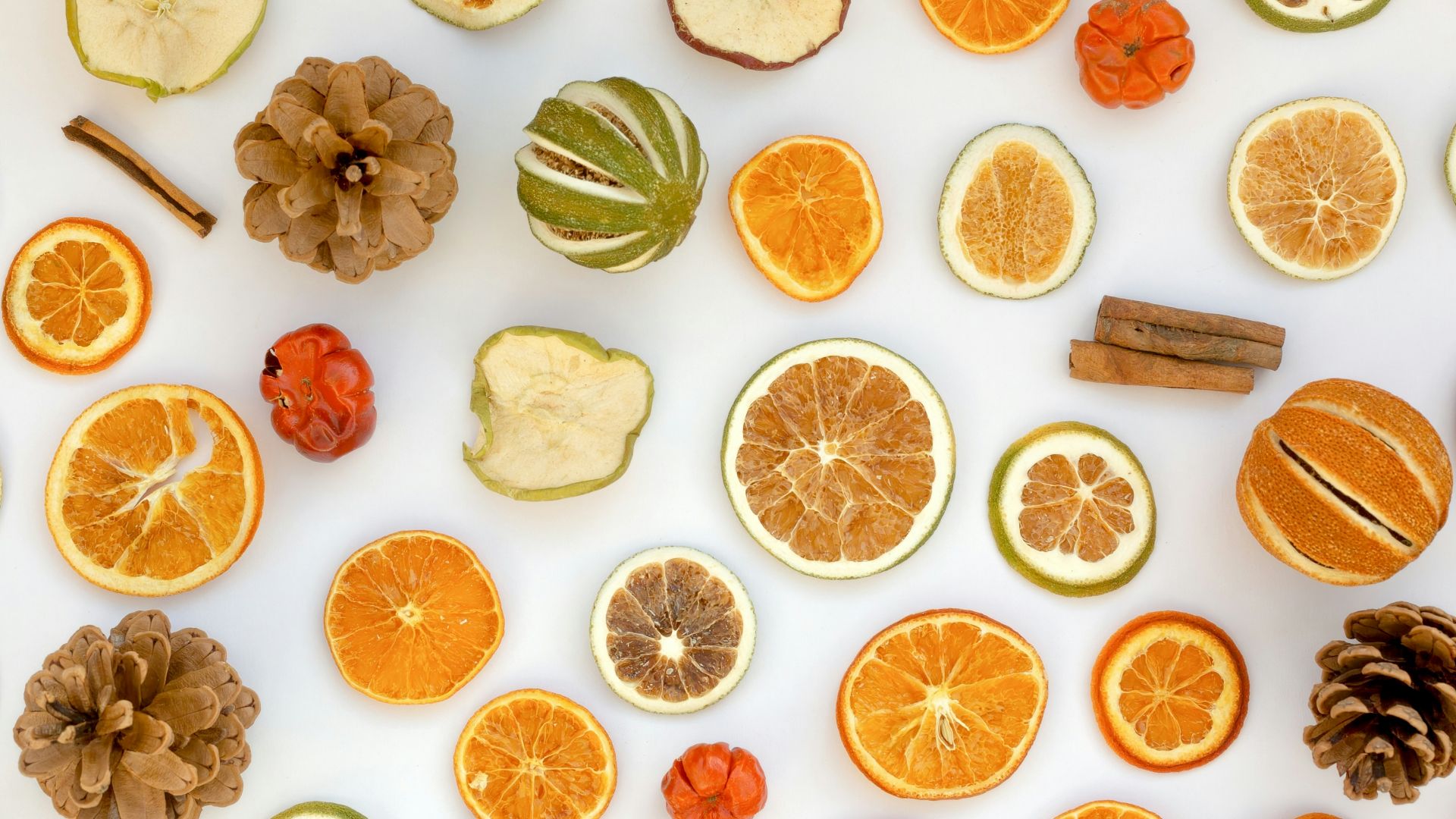 orange slices, cinnamons, and pine cones arranged on a white surface