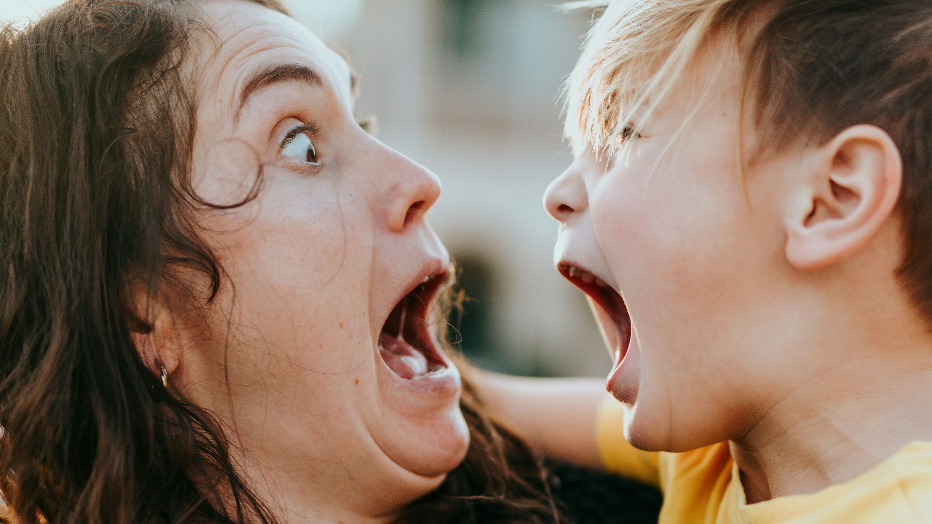 woman in black sweater kissing girl in yellow shirt