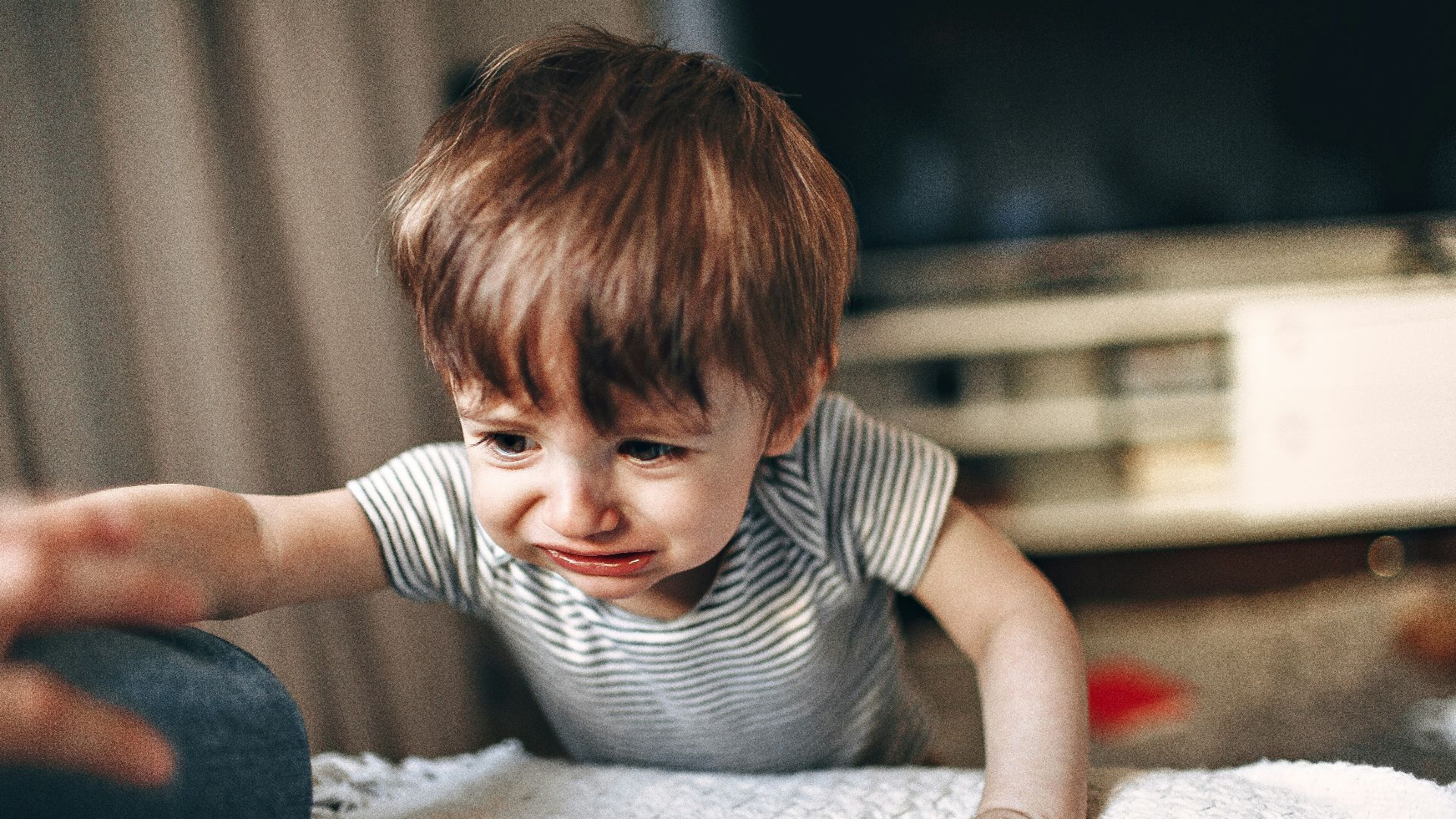 boy in black and white striped crew neck t-shirt sitting on white and gray bed