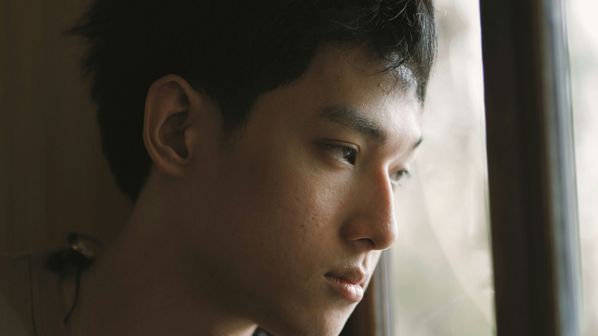 a man looking out of a window with a serious look on his face