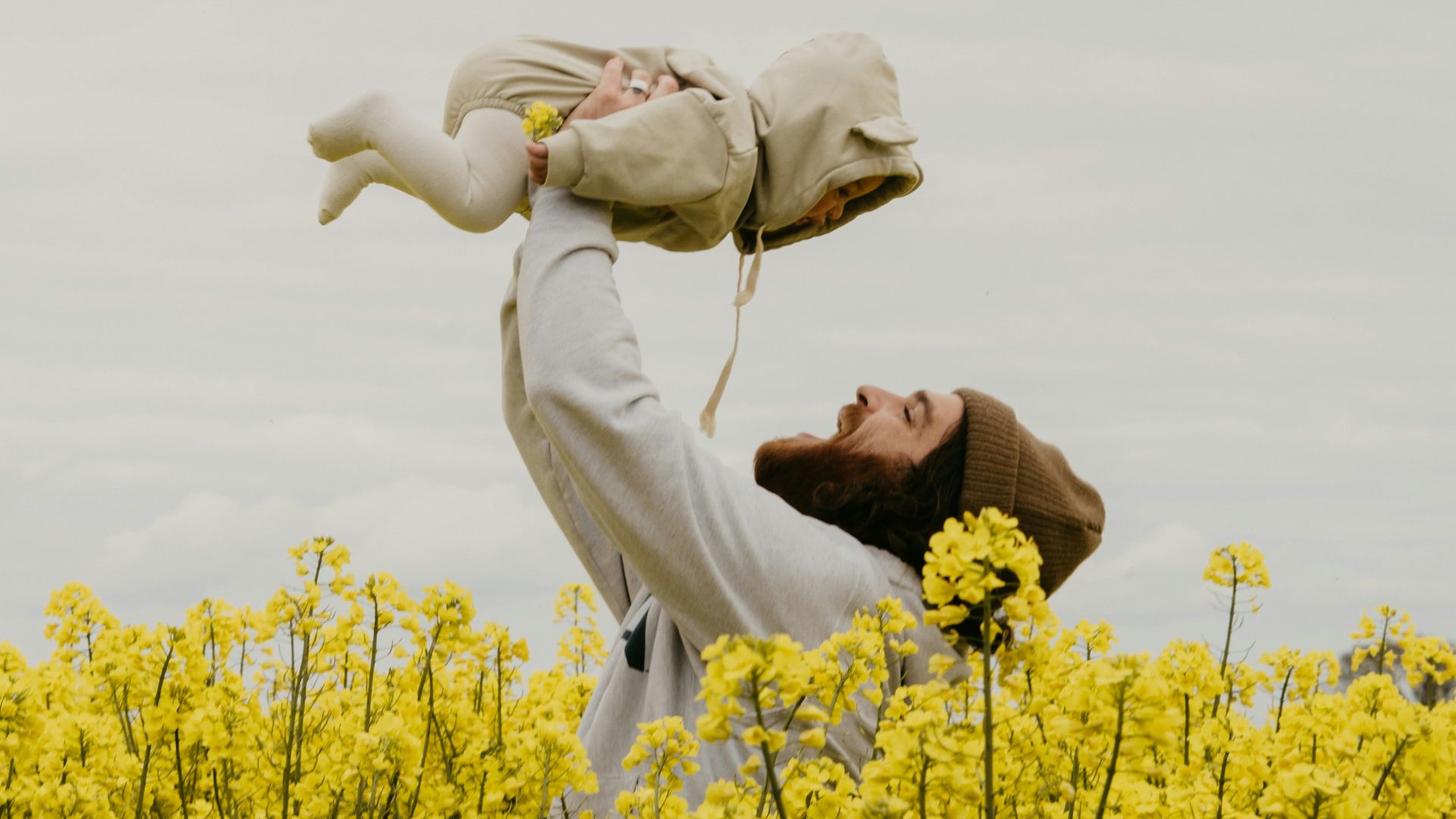 a person holding a baby in a field of yellow flowers