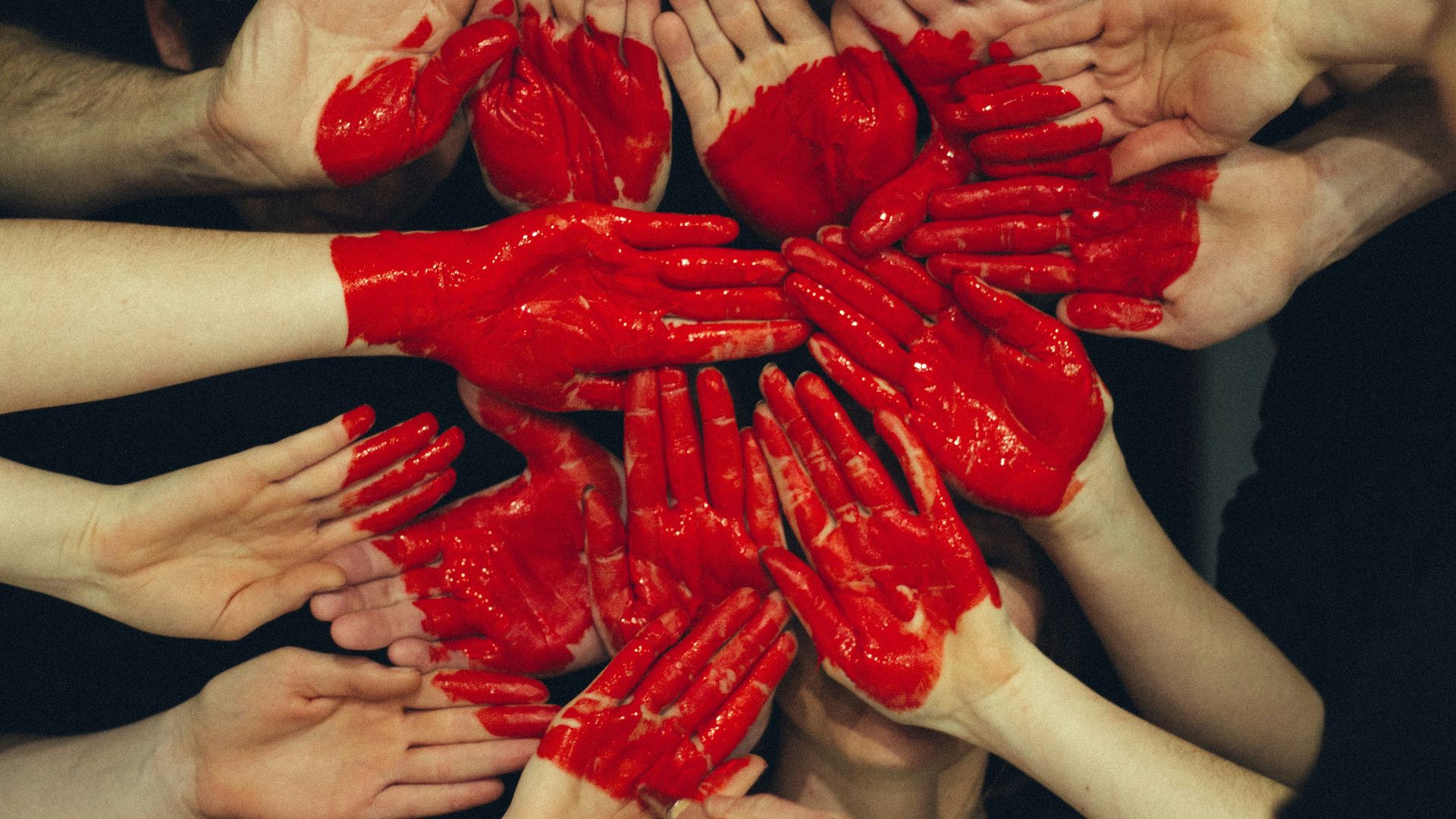 hands formed together with red heart paint