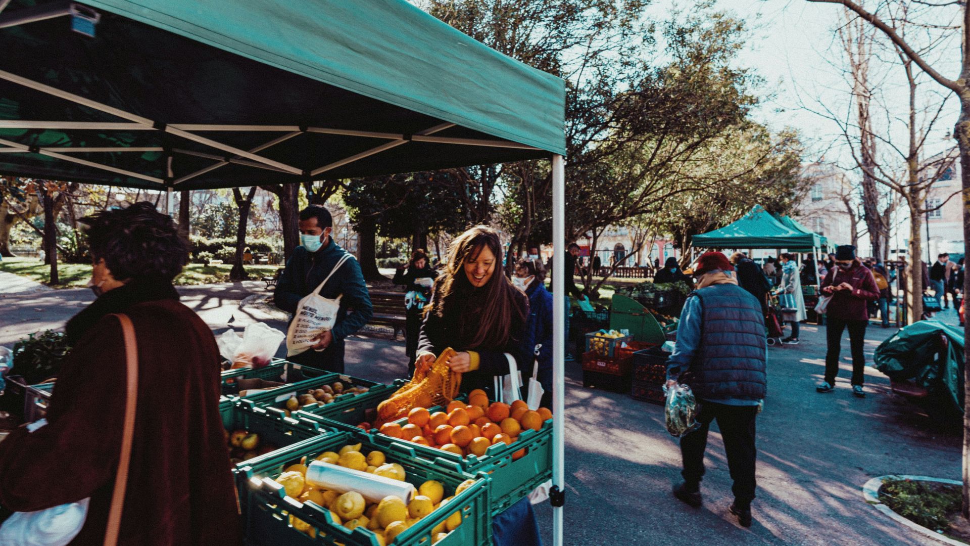 a group of people standing around a fruit stand