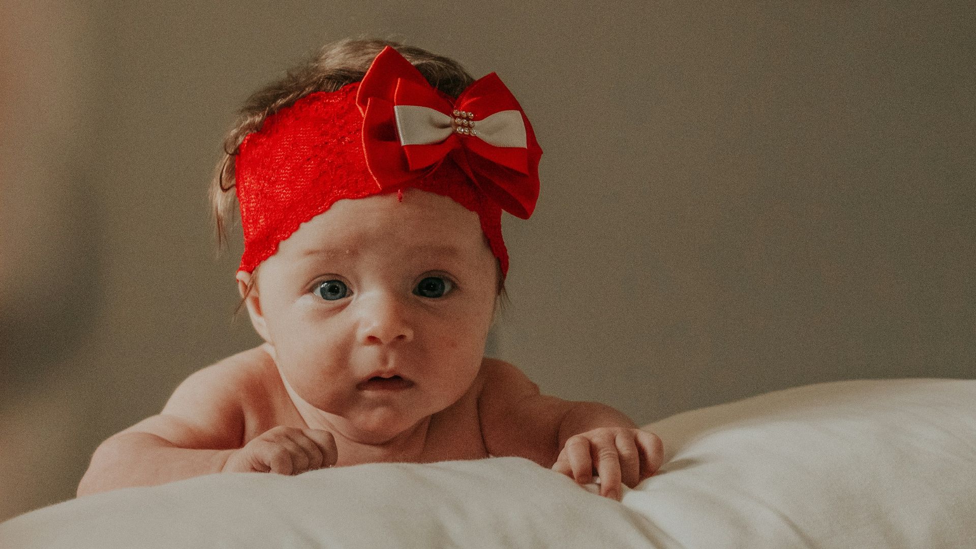 baby in red headband lying on bed