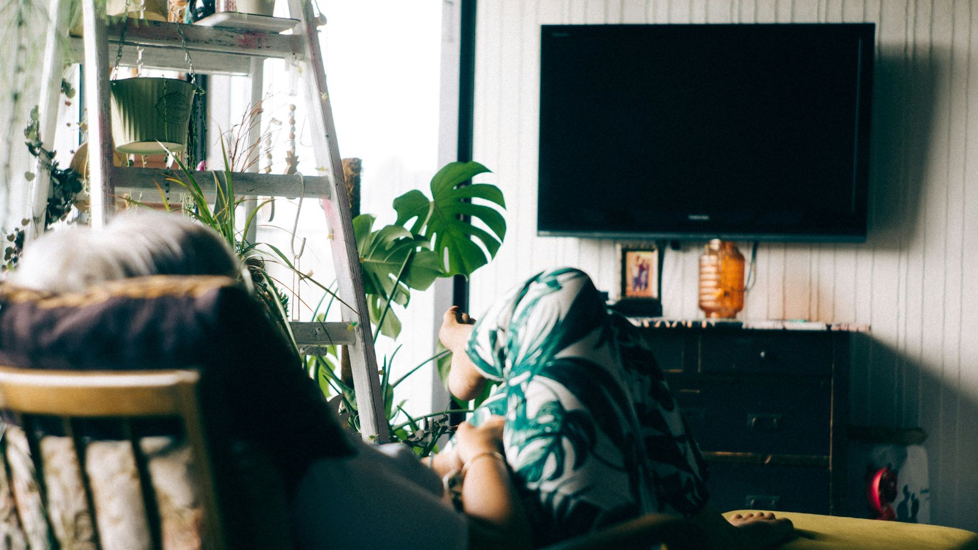 woman sitting on armchair staring at turned-off TV