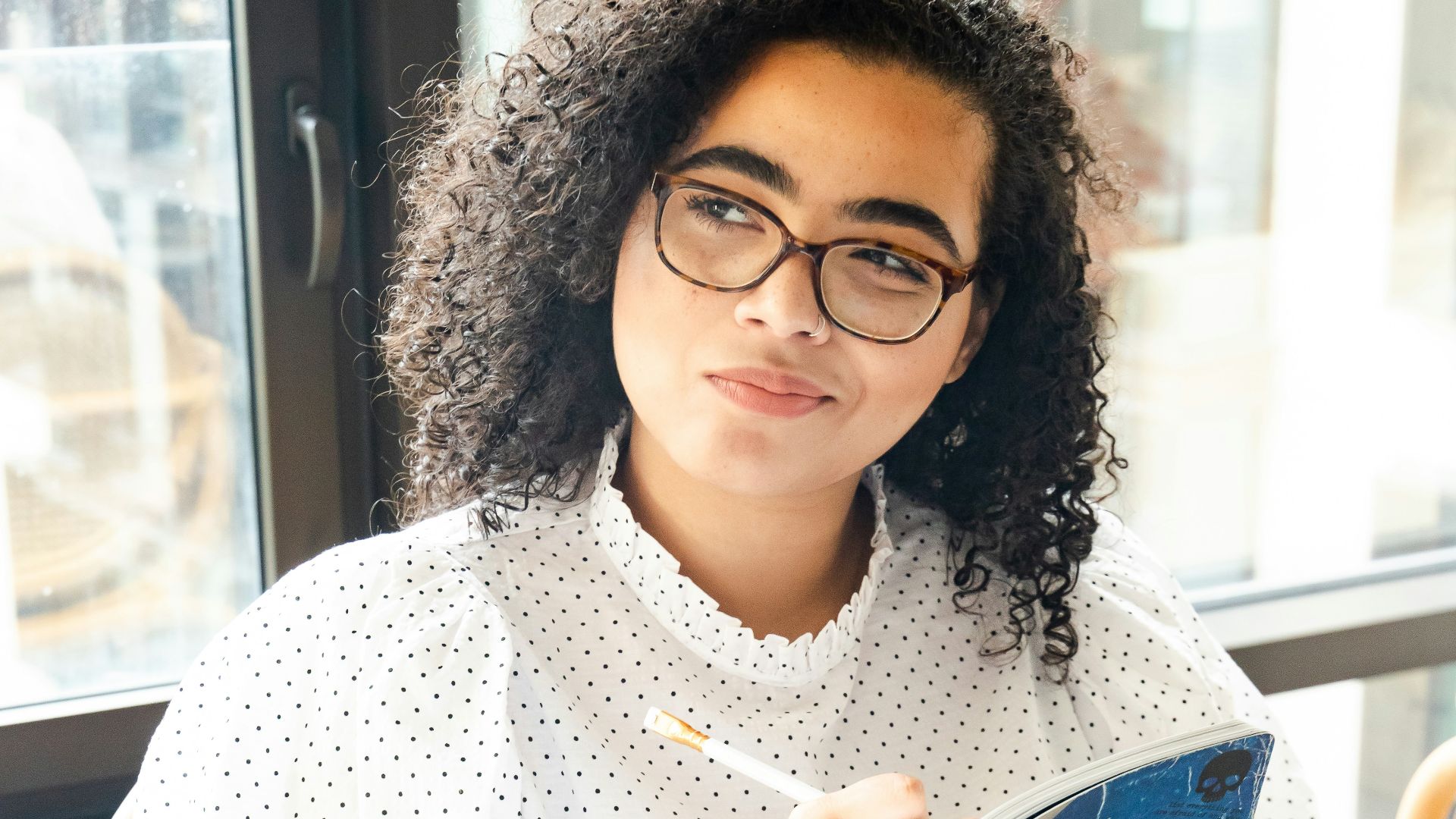 woman in white and black polka dot shirt holding blue and white book