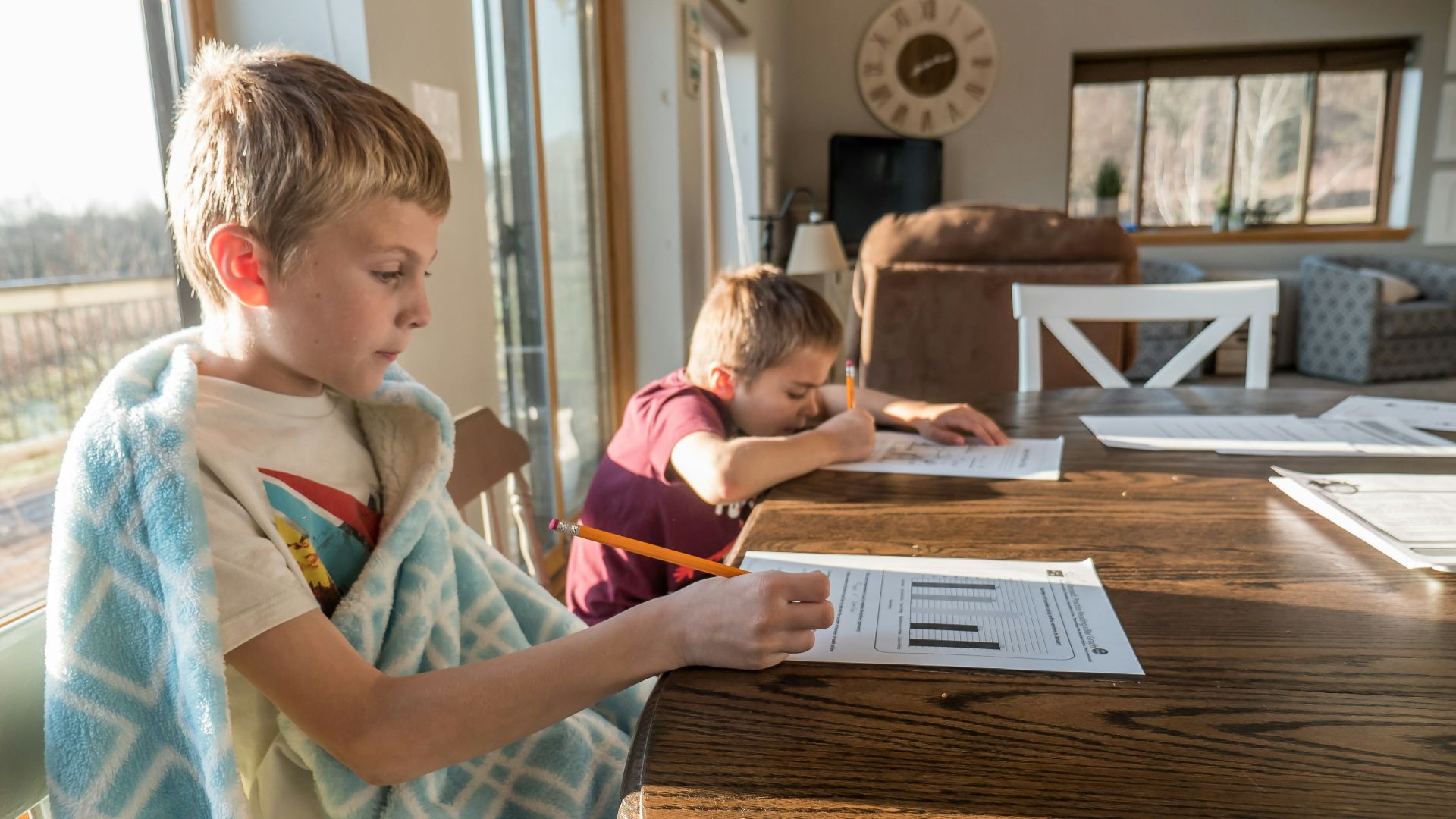 boy in white green and blue plaid button up shirt writing on white paper