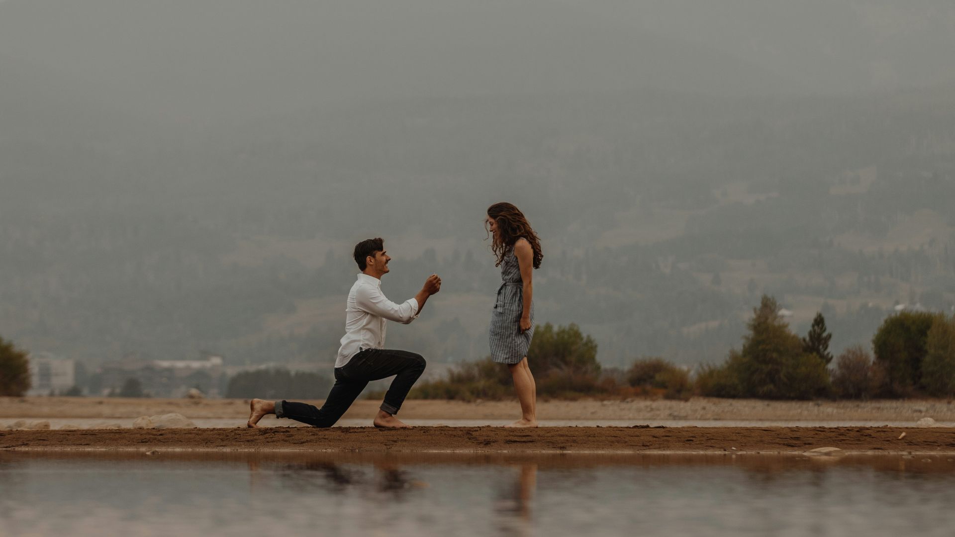 man in white shirt and black pants sitting on brown wooden dock during daytime