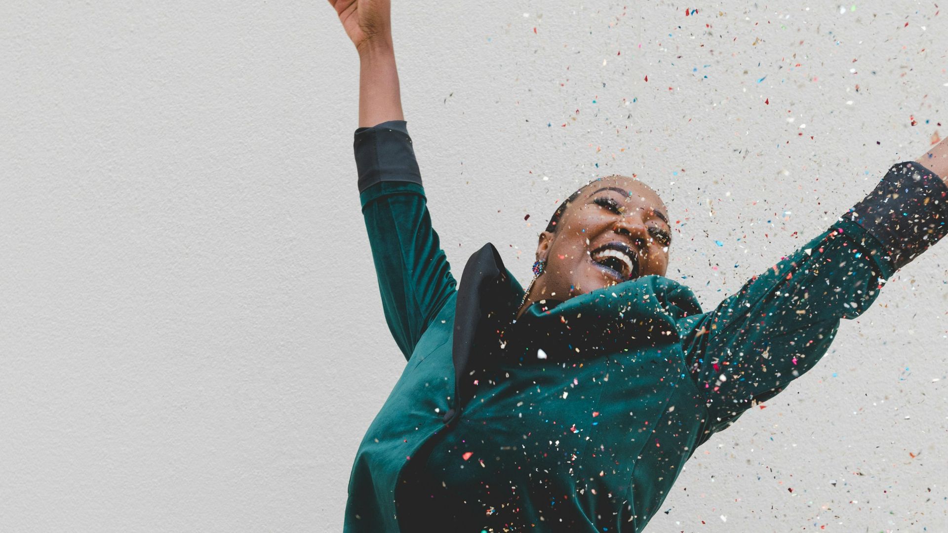 woman in green jacket raising her hands