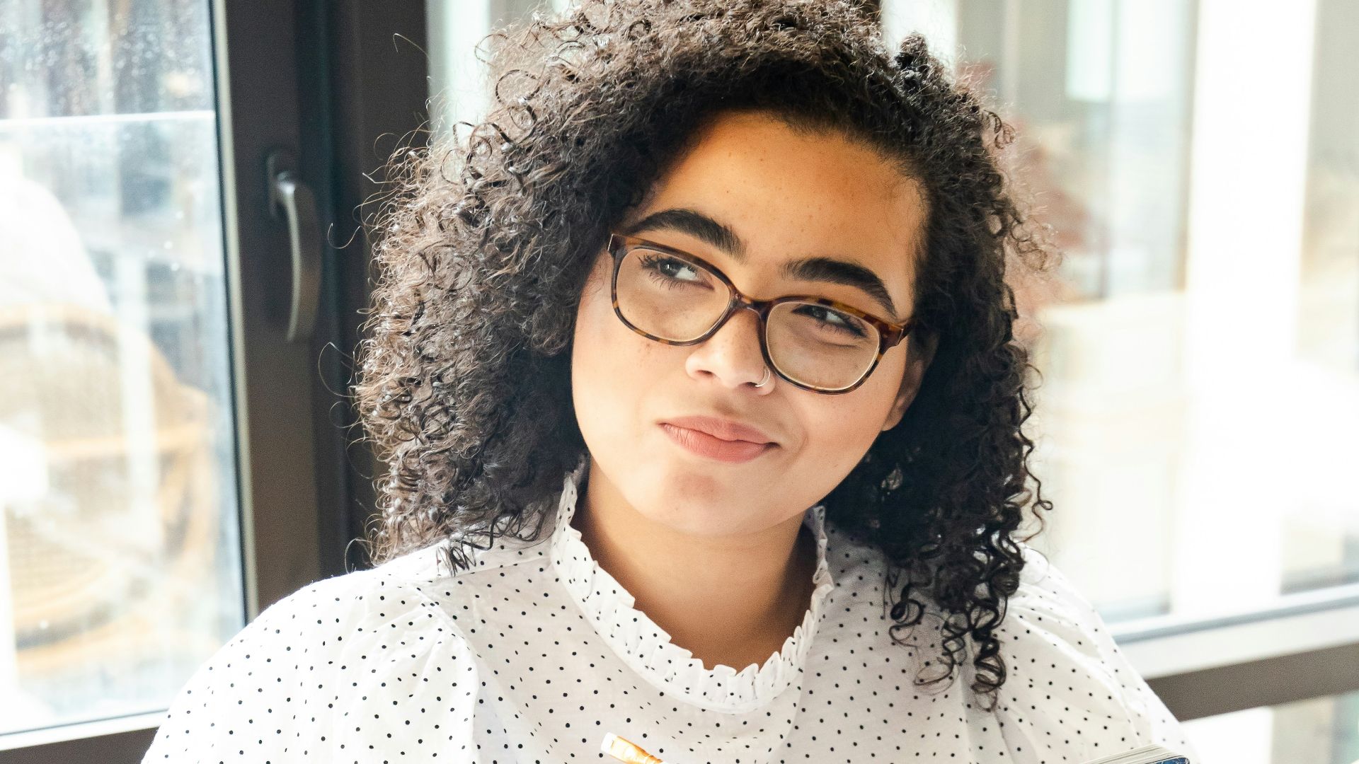 woman in white and black polka dot shirt holding blue and white book
