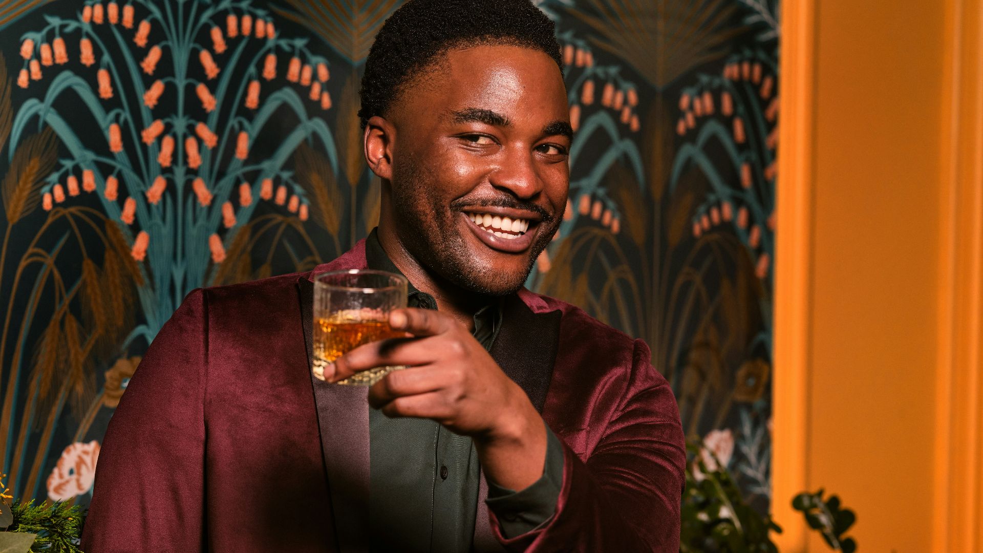 a man in a red jacket holding a drink