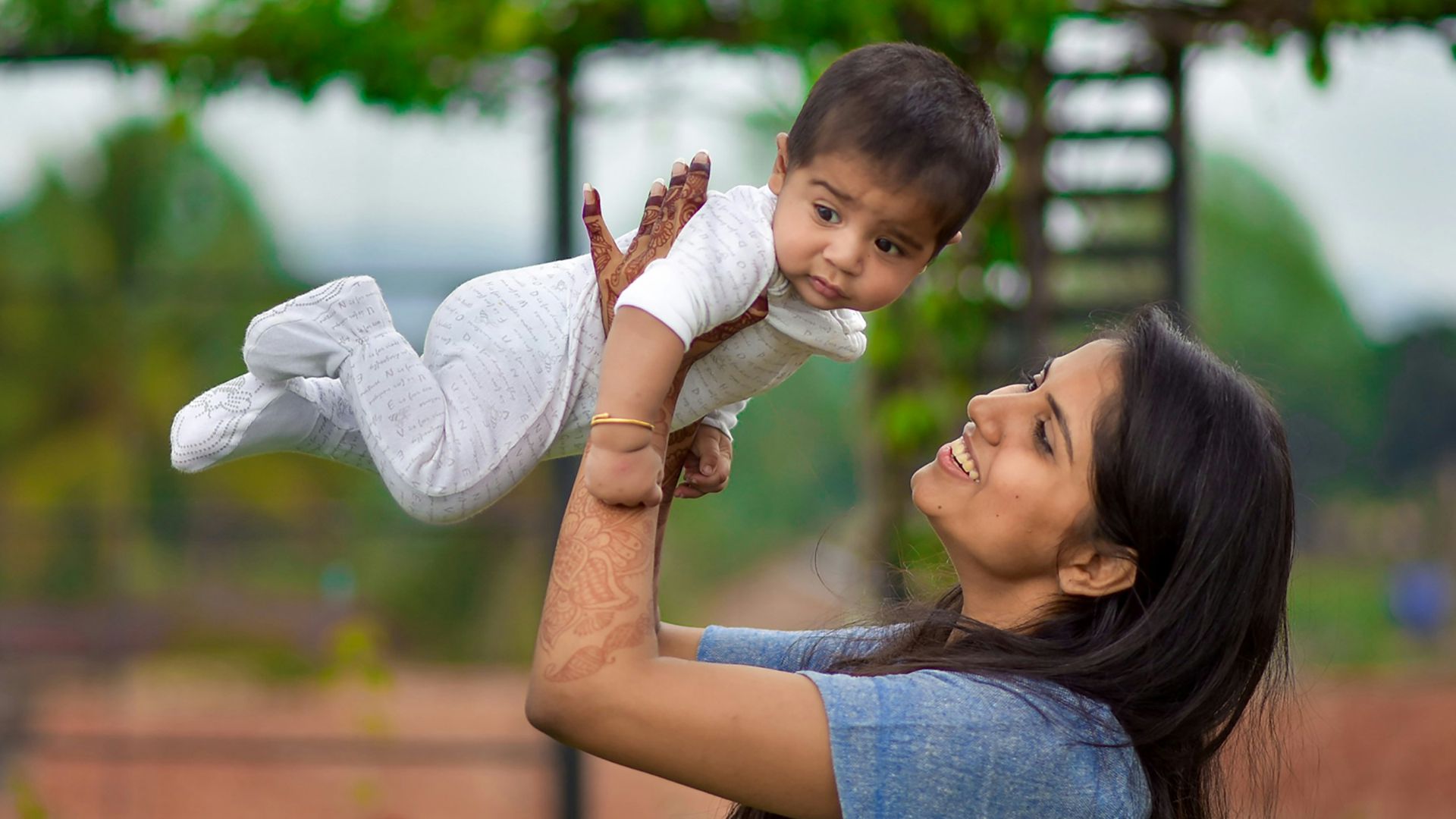 woman in blue denim button up shirt carrying girl in white long sleeve shirt during daytime