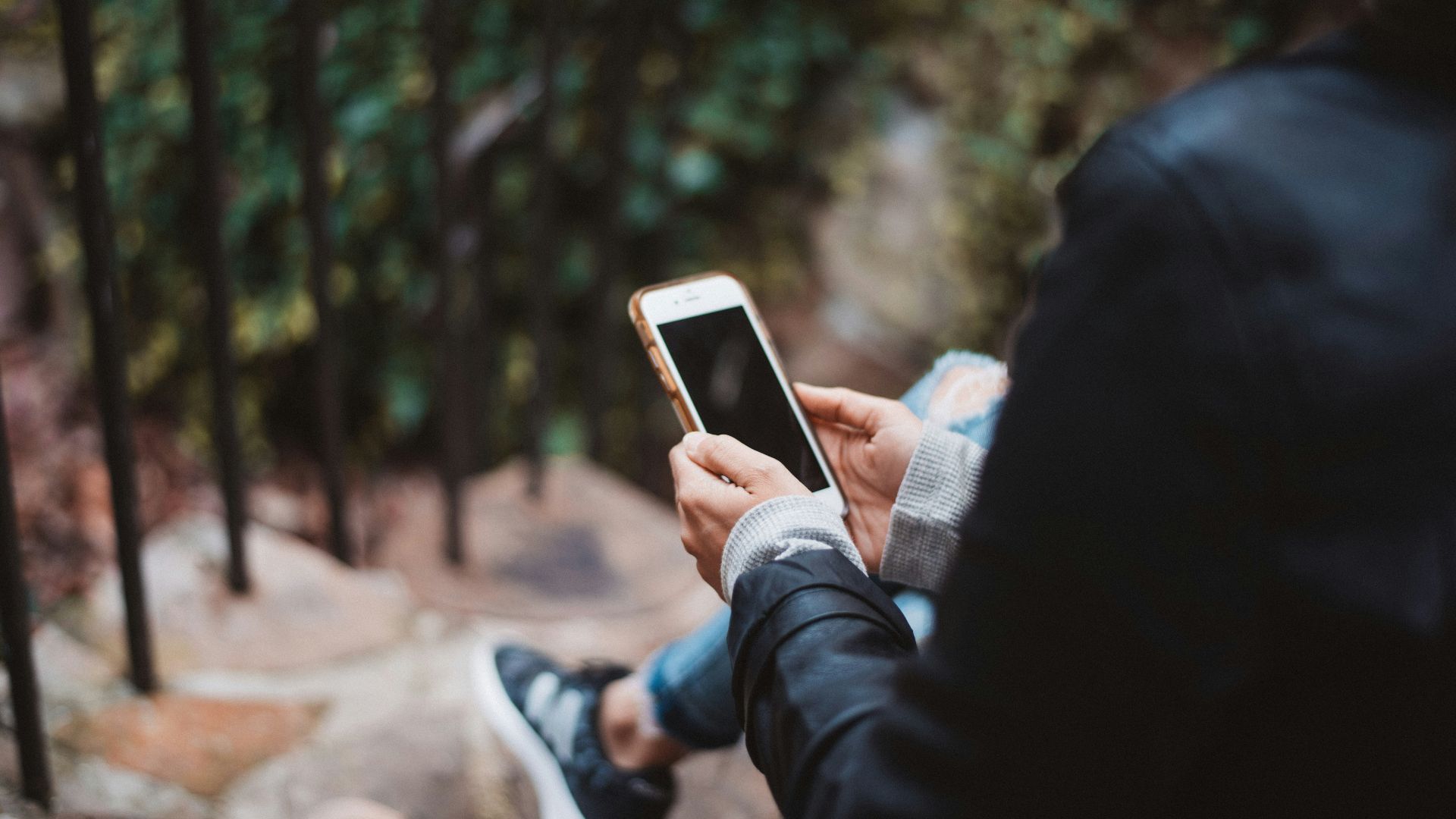 person holding white smartphone sitting on stair