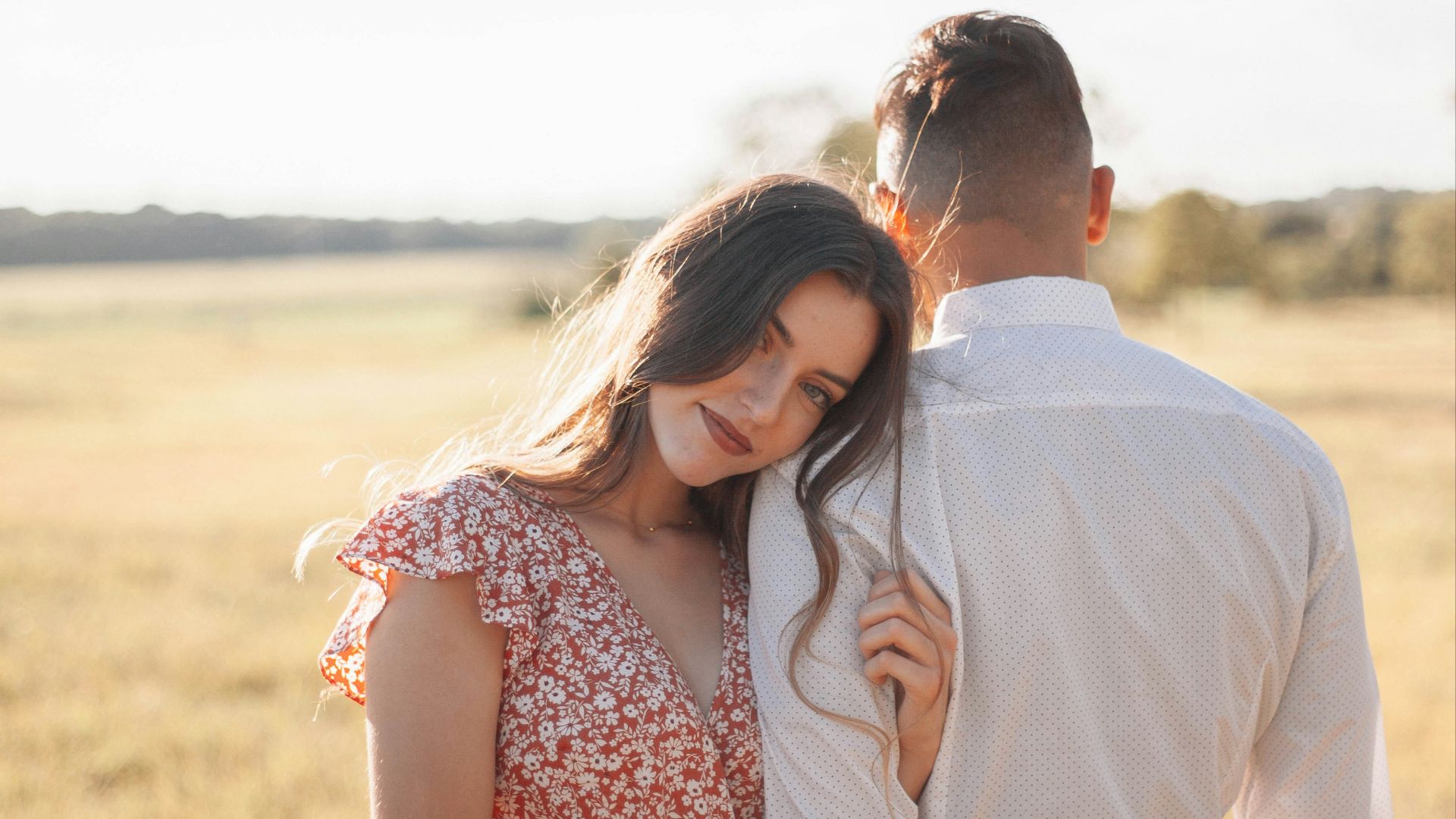 man in white dress shirt kissing woman in red and white floral dress