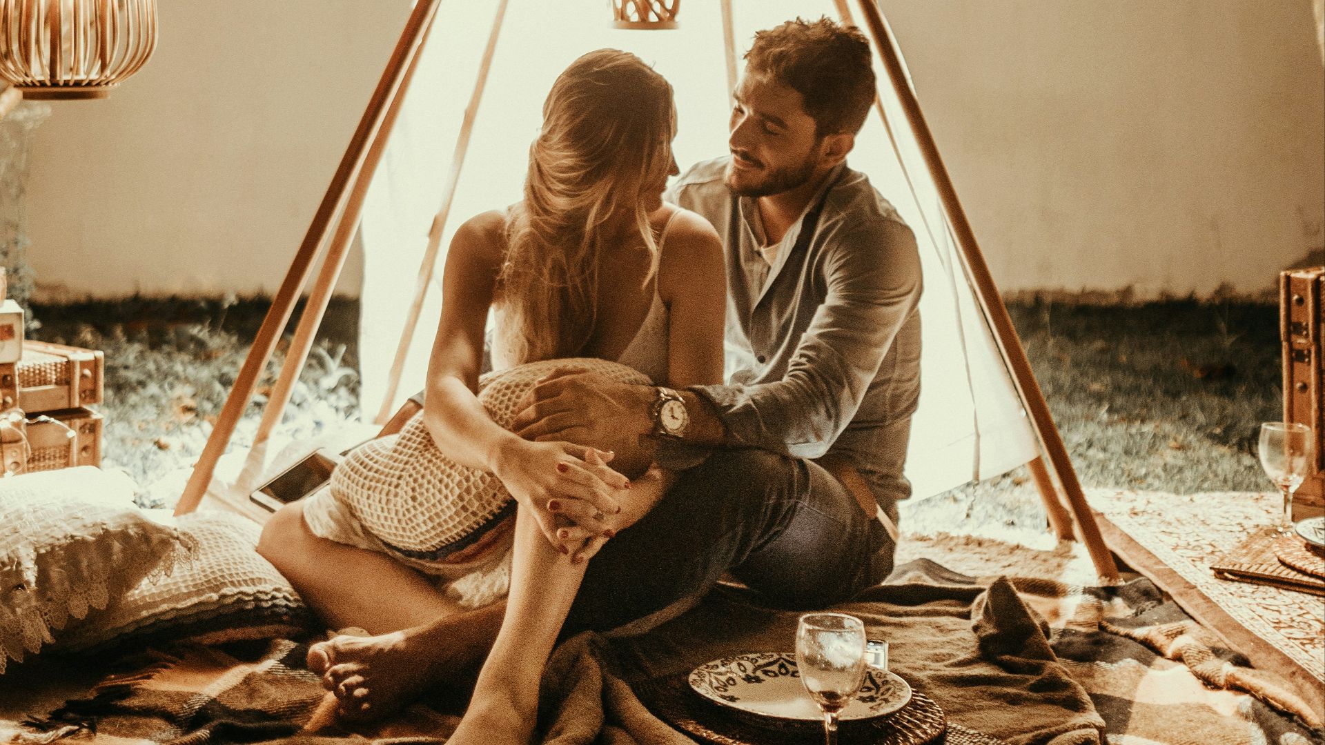 couple sitting inside tepee hut with lights