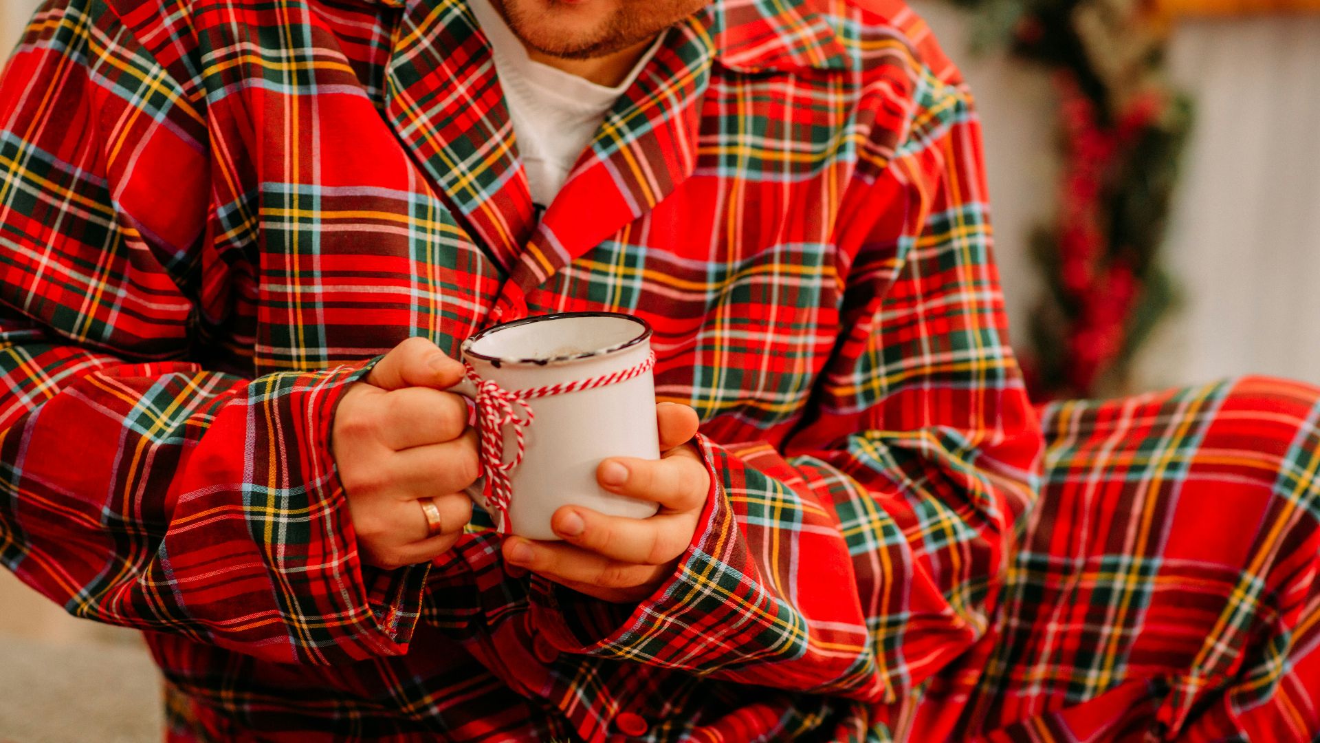 man in red and black plaid dress shirt holding white ceramic mug