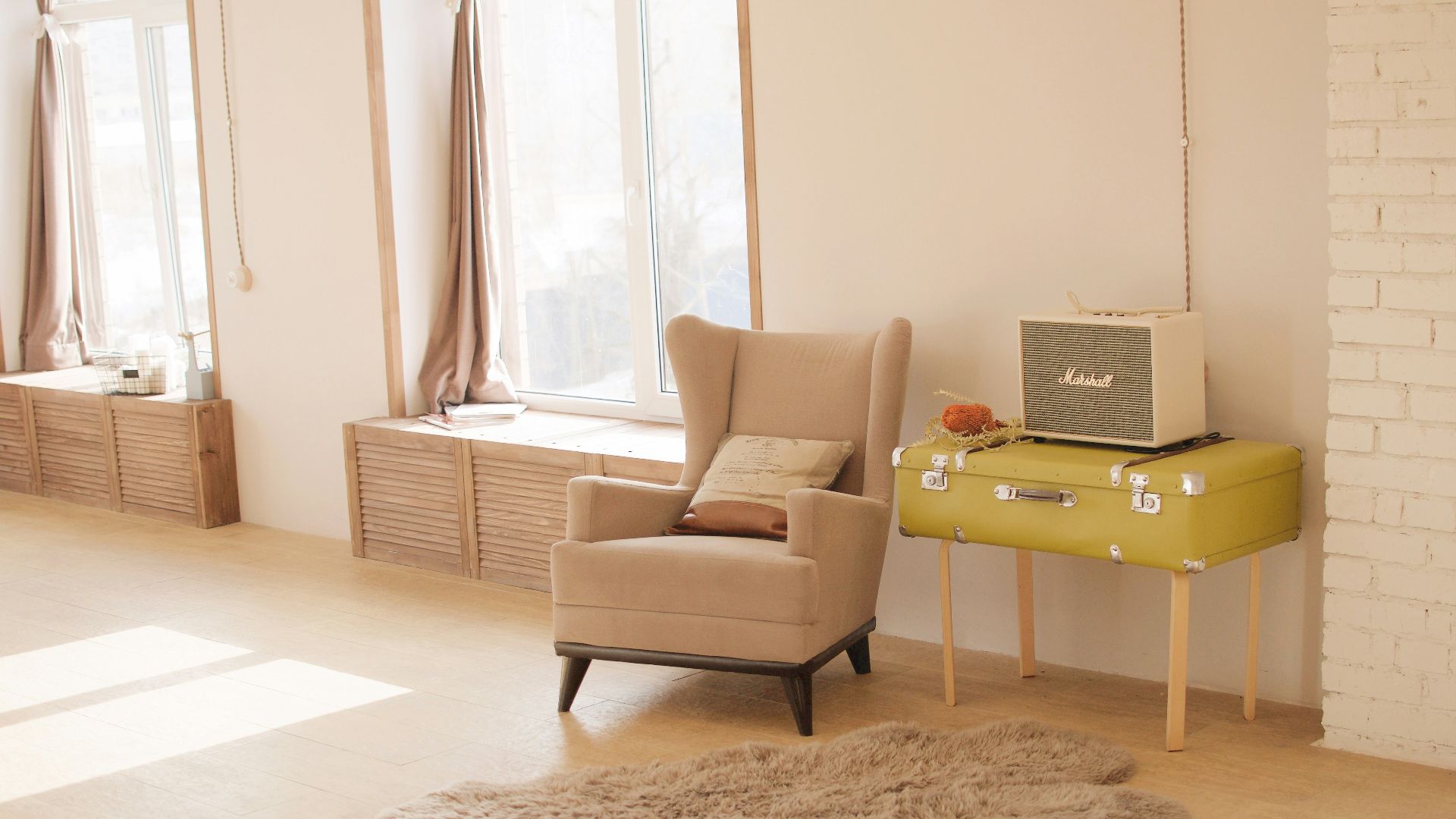 wing chair beside suitcase and window