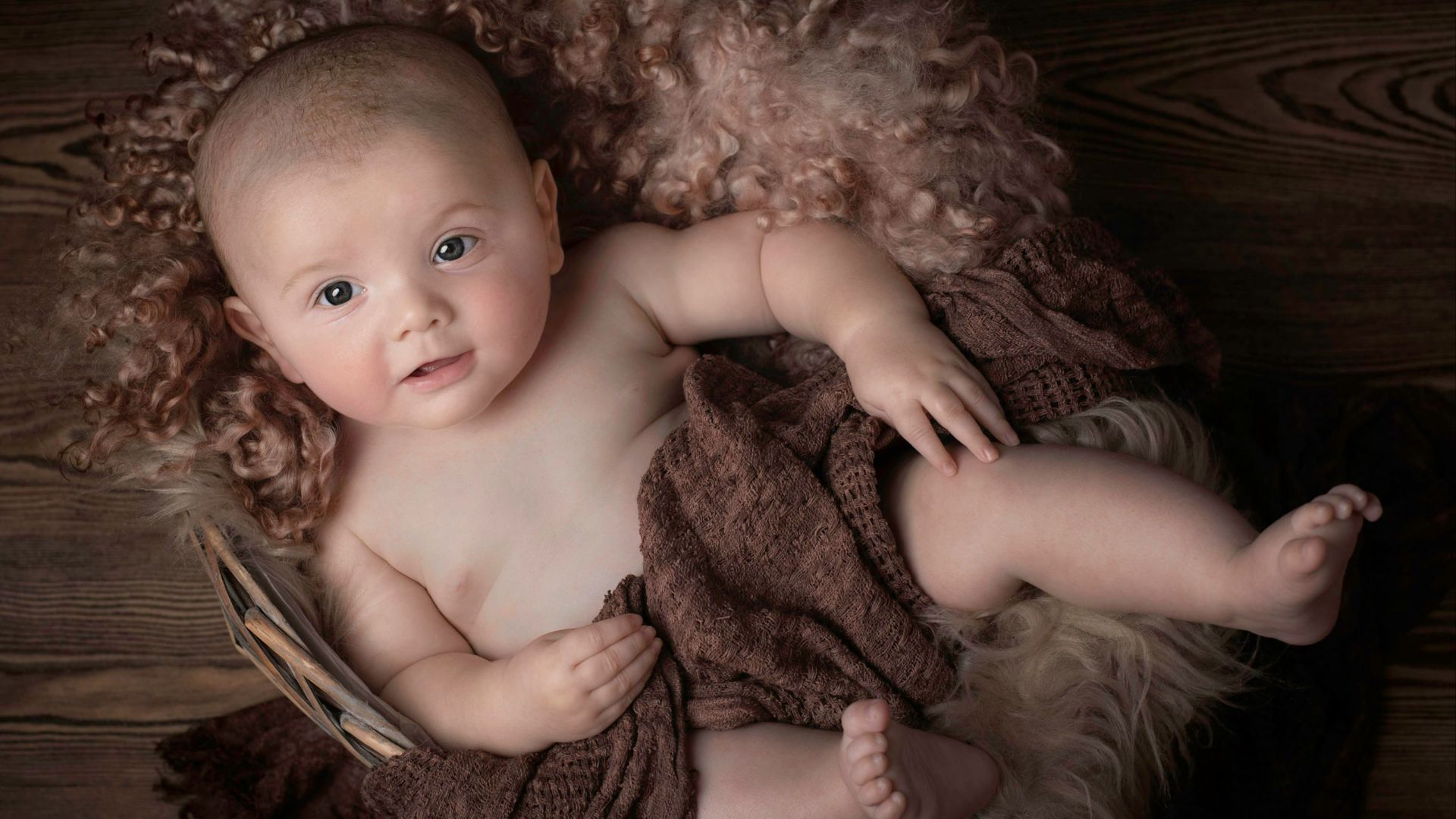 baby lying on brown textile