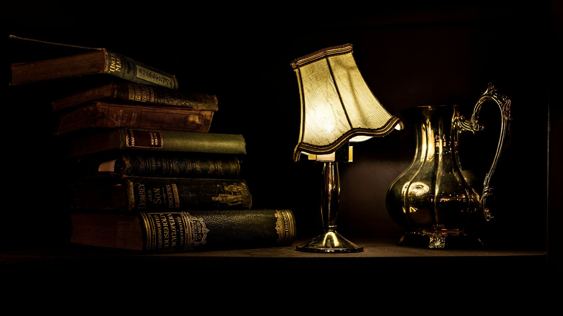 turned on desk lamp beside pile of books